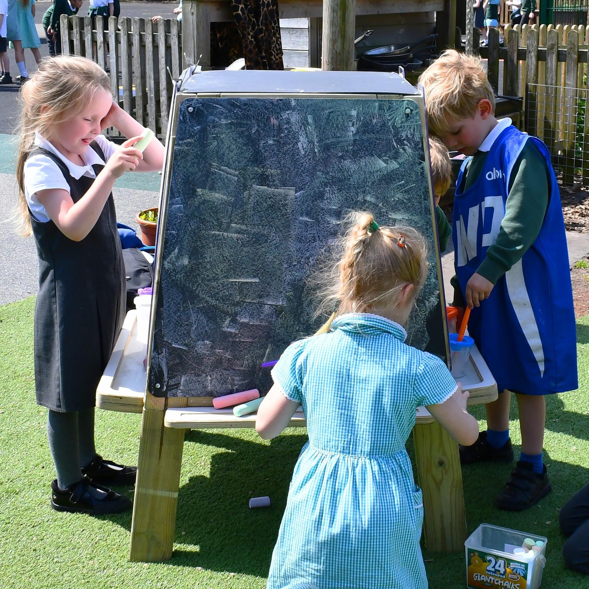 Four children are each stood on a different side of the Group Art Easel as they make art.