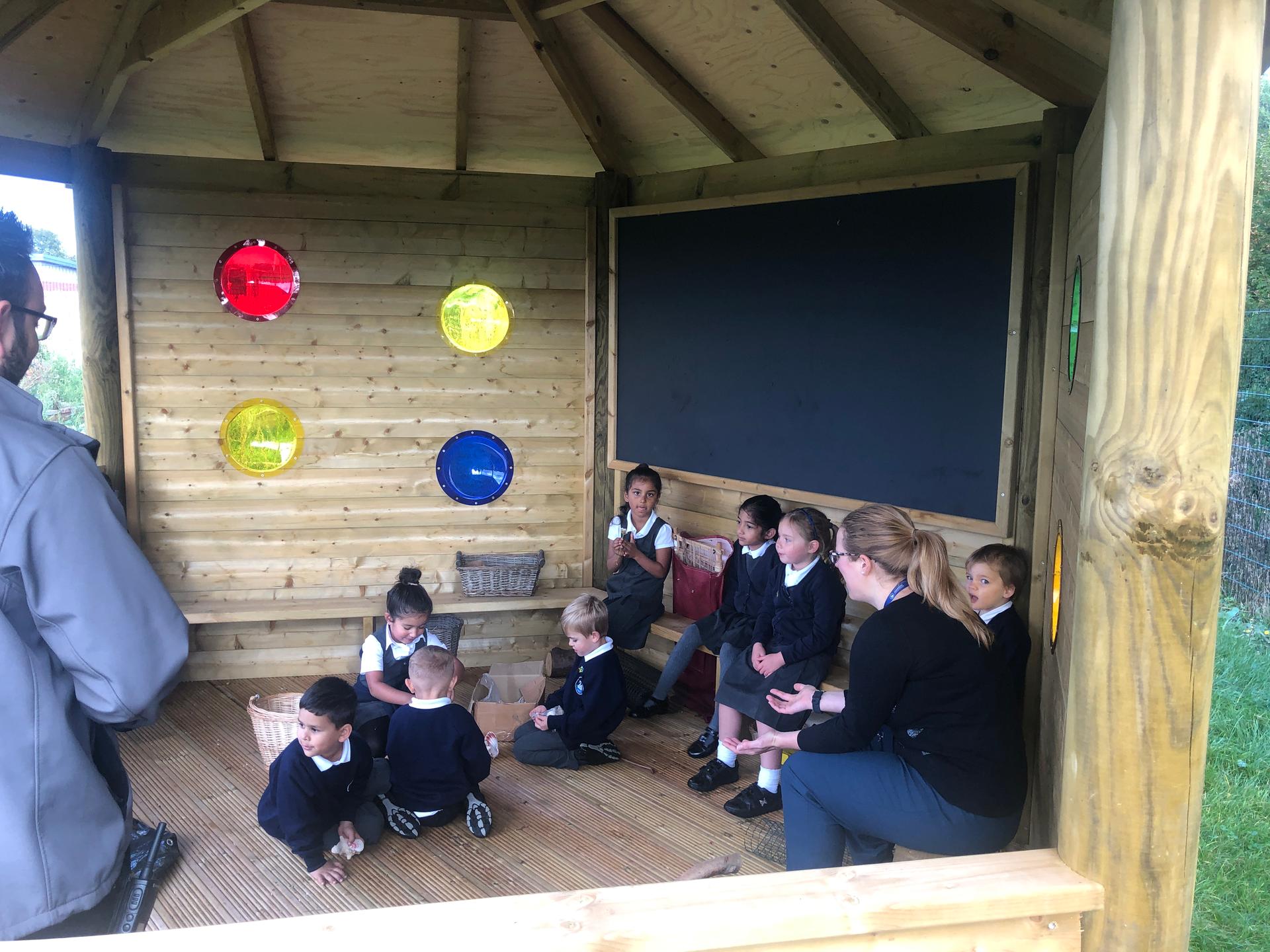 A group of children sitting inside the Sensory 5M Hexagonal Gazebo