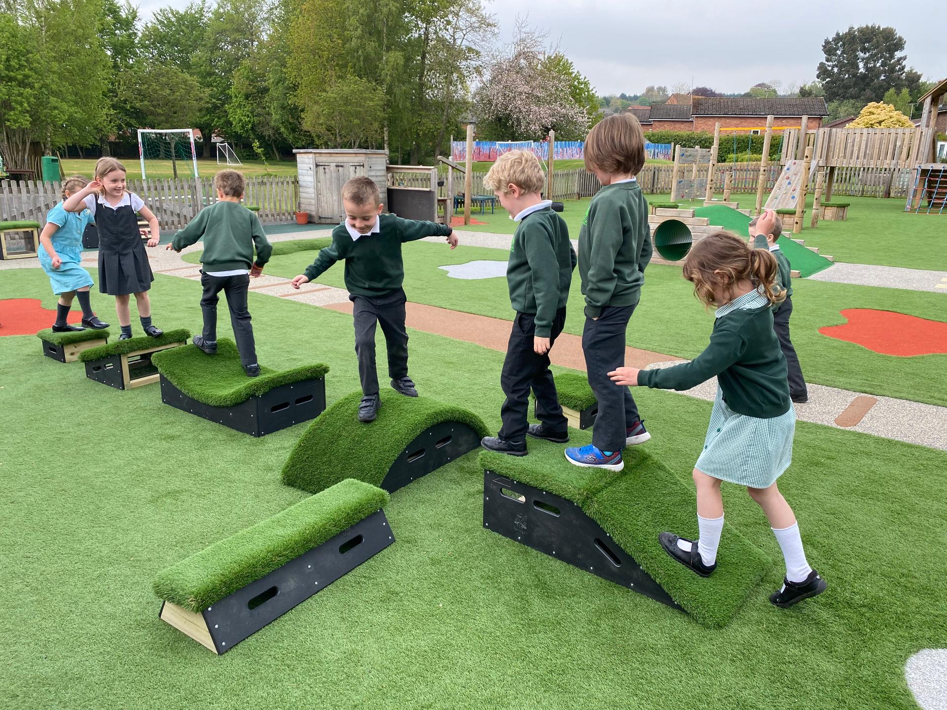 School children playing on grass-topped Get Set, Go! Blocks in the playground.