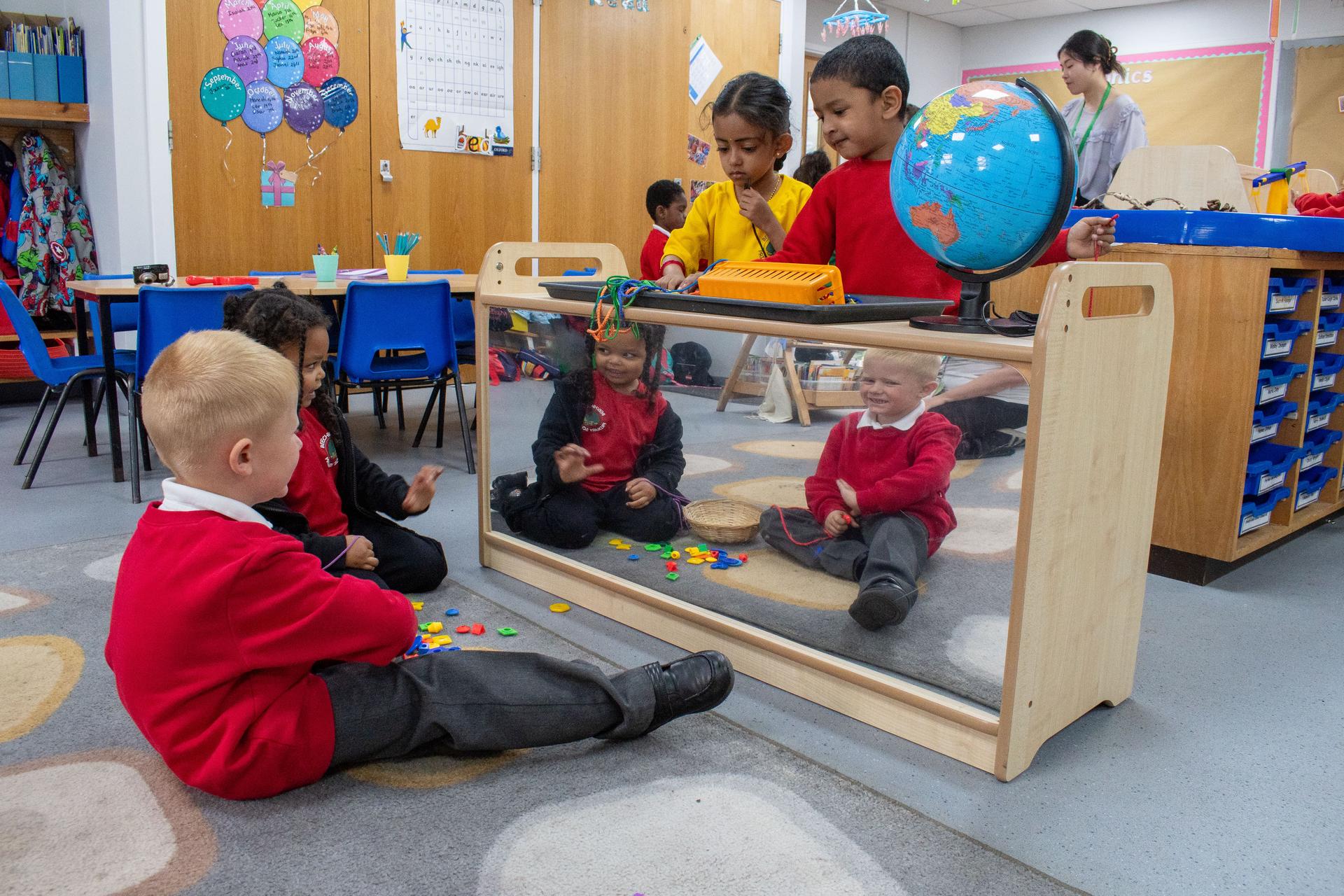 children looking into mirror back unit in classroom