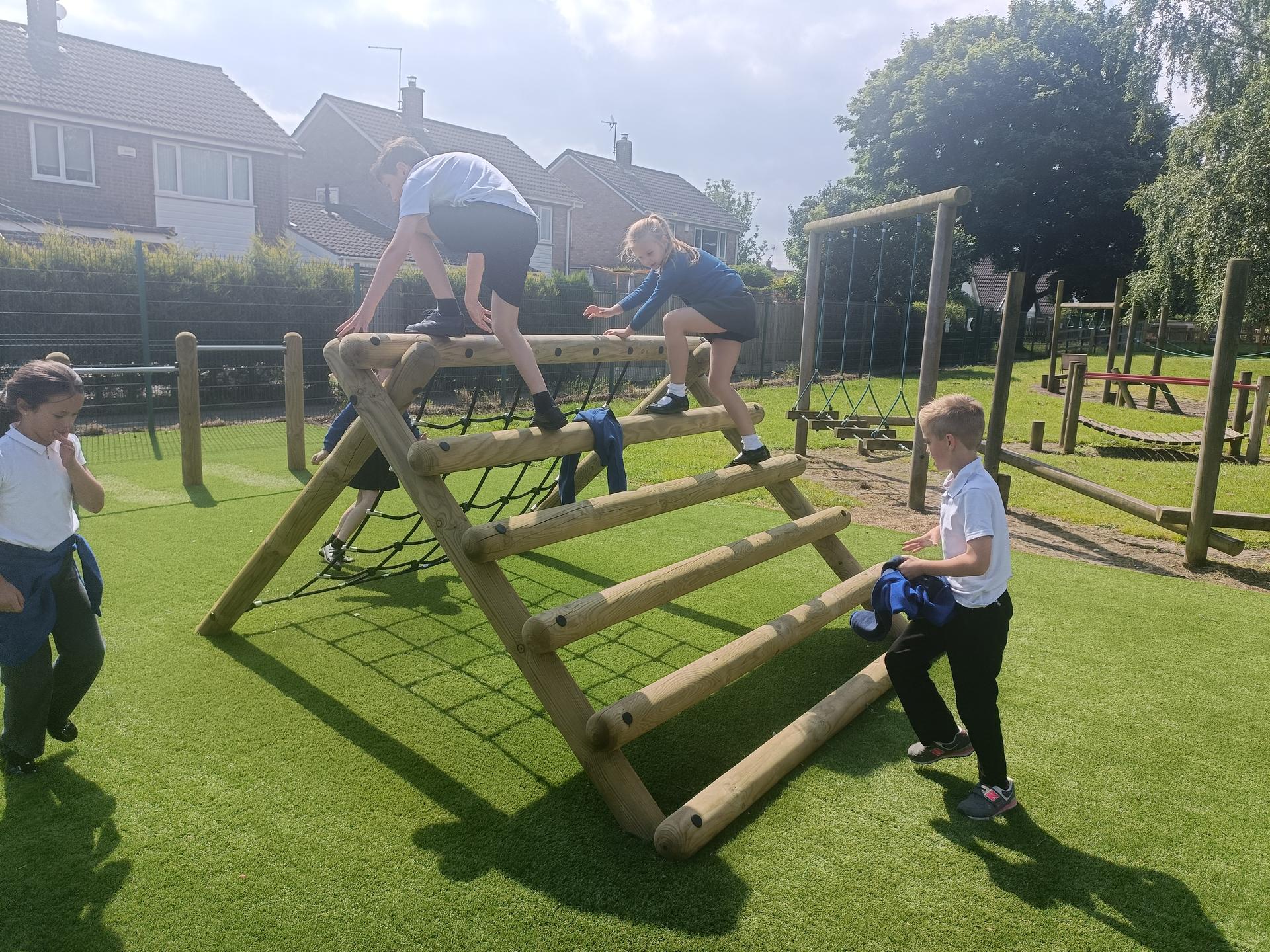 The Forest Log Climber with a net installed on artificial grass with children climbing it.