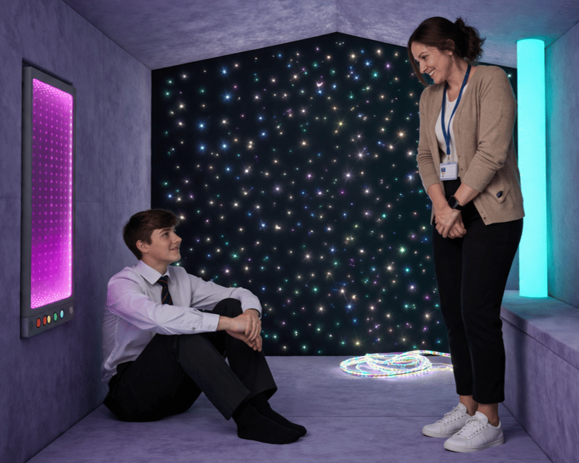 A teacher and a student are inside the sensory nook, talking to each other.