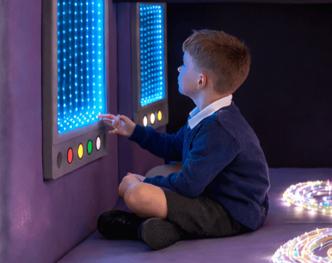A young boy is playing with an LED infinity mirror.