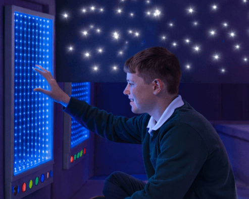 Child playing with LED infinity mirror within the Sensory Nook.