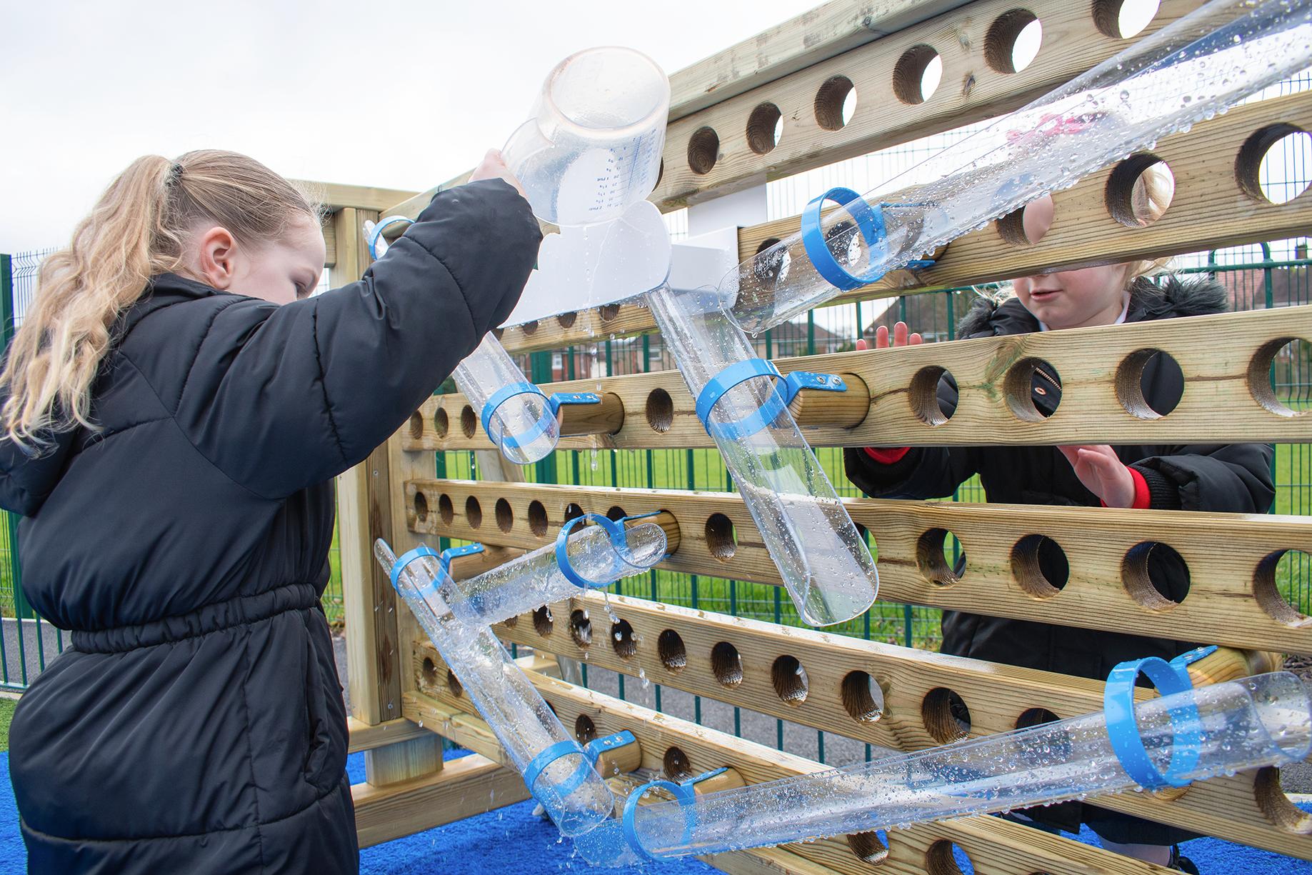 A girl pouring water from a plastic jug into a water channel
