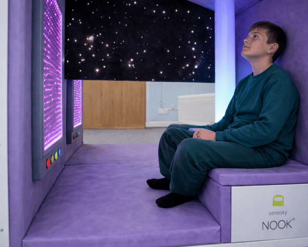A SEN boy is looking towards the ceiling as he is sat inside the Sensory Nook.