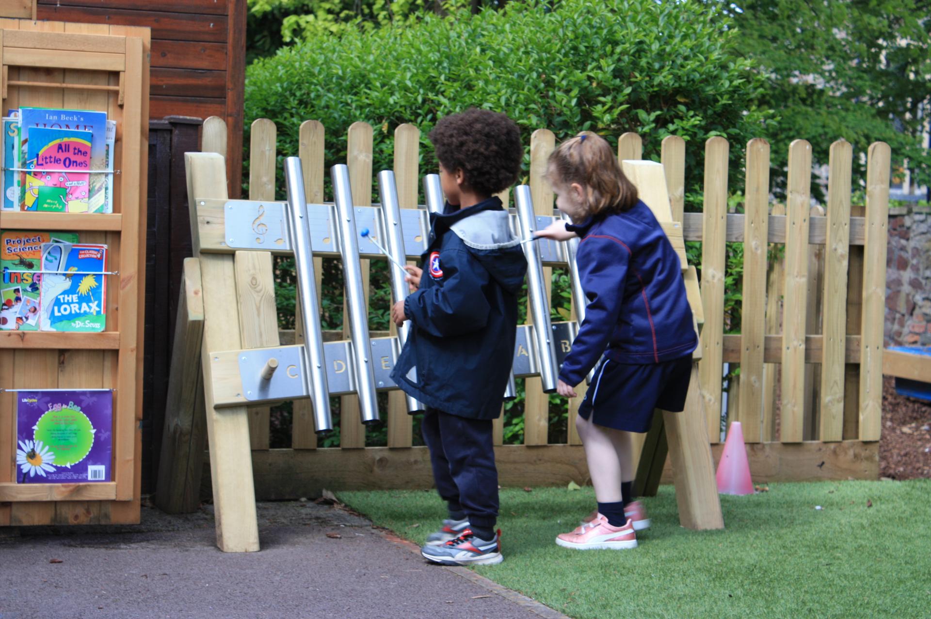 Two children playing together on the mini freestanding chimes.