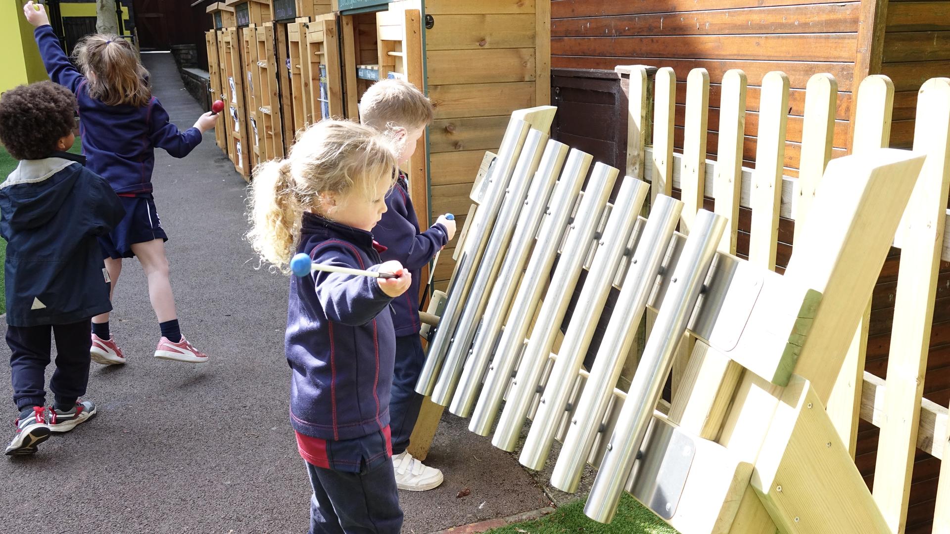 Young girl enjoying musical play on the mini freestanding chimes.