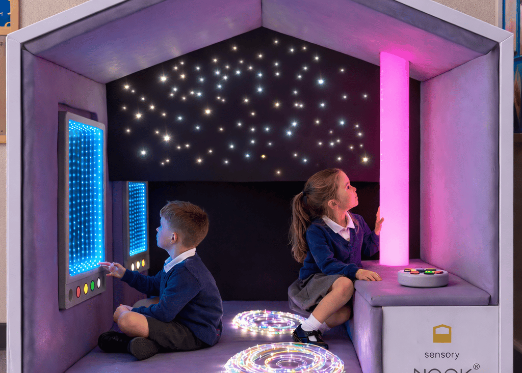 Two children are sat within the Sensory Nook Interactive (standard), admiring the lights.