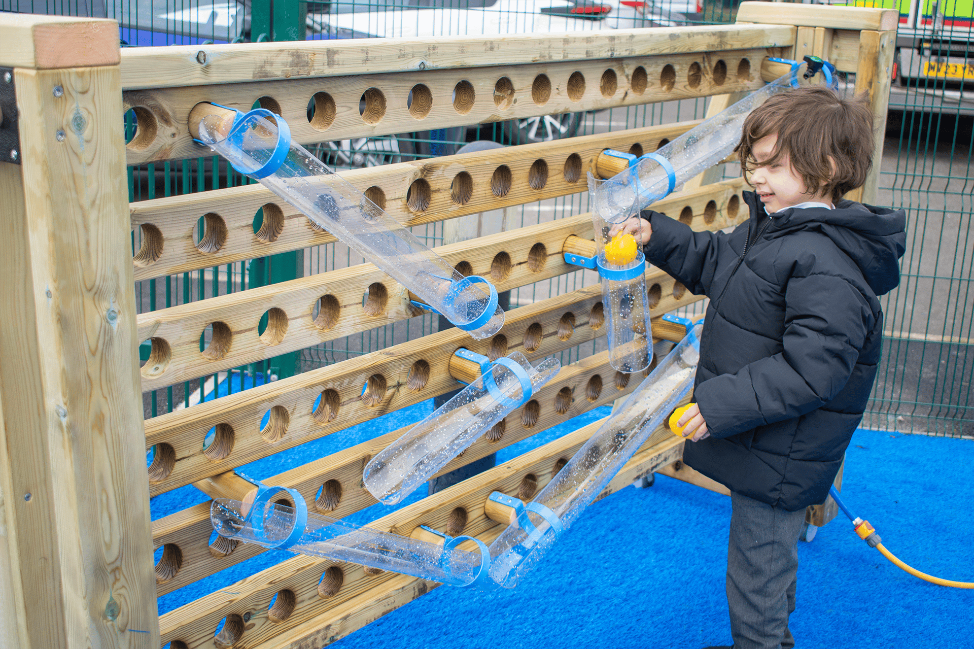 A boy tilting the water channels on the movable water wall to make the ball and water flow a certain direction