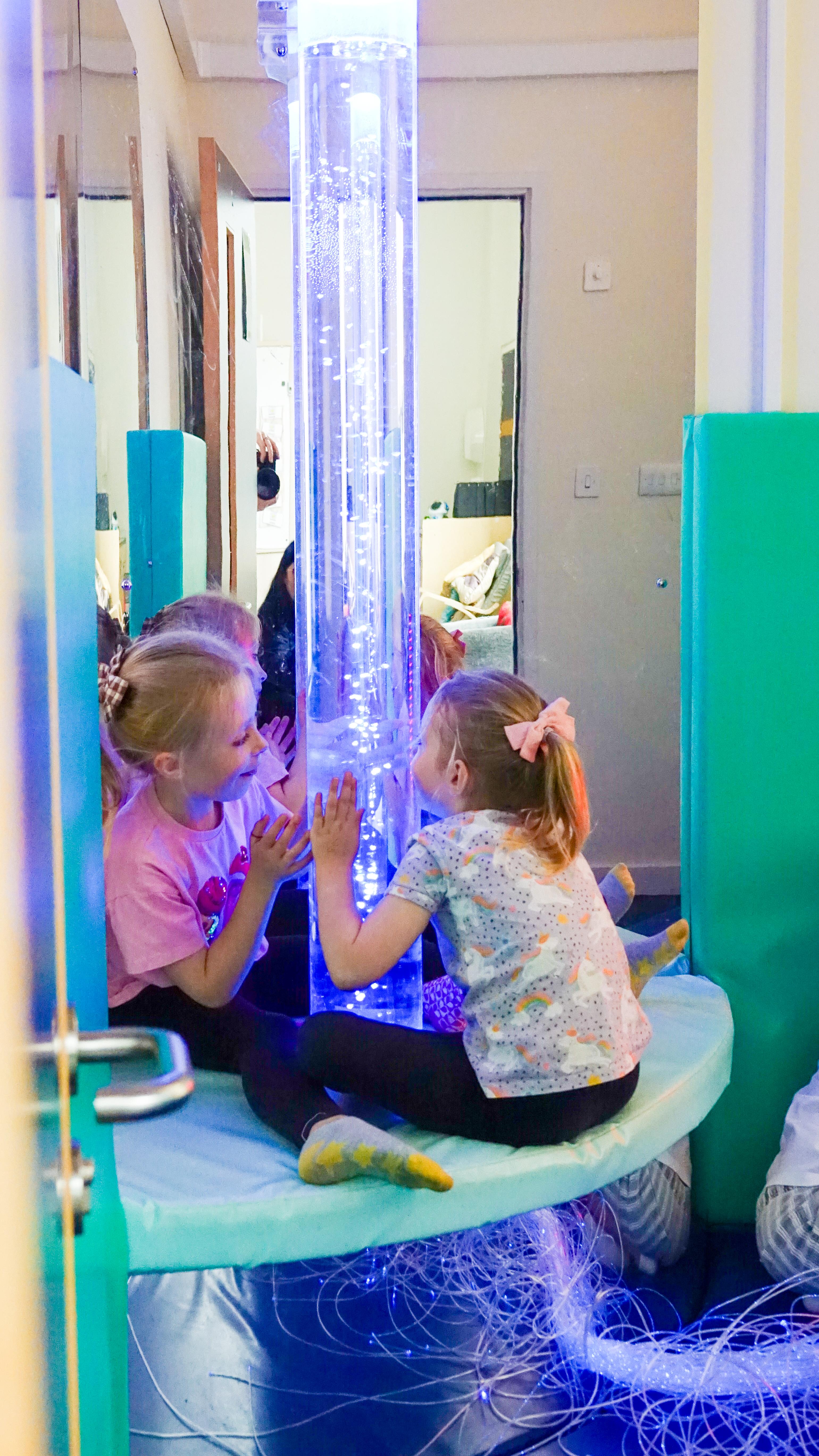 Two young girls playing with a large sensory bubble tube