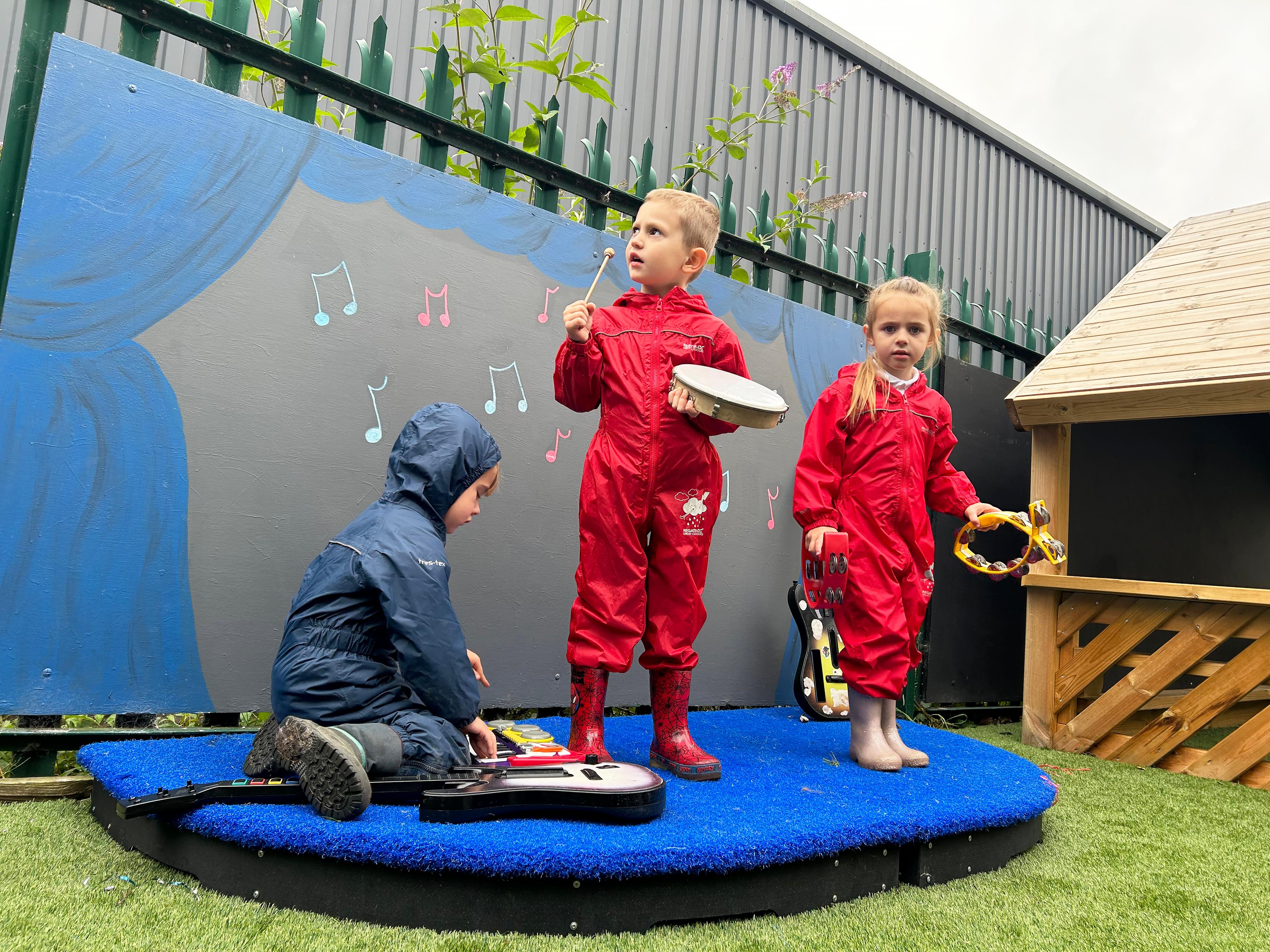 Children playing musical instruments on a blue dual freestanding stag