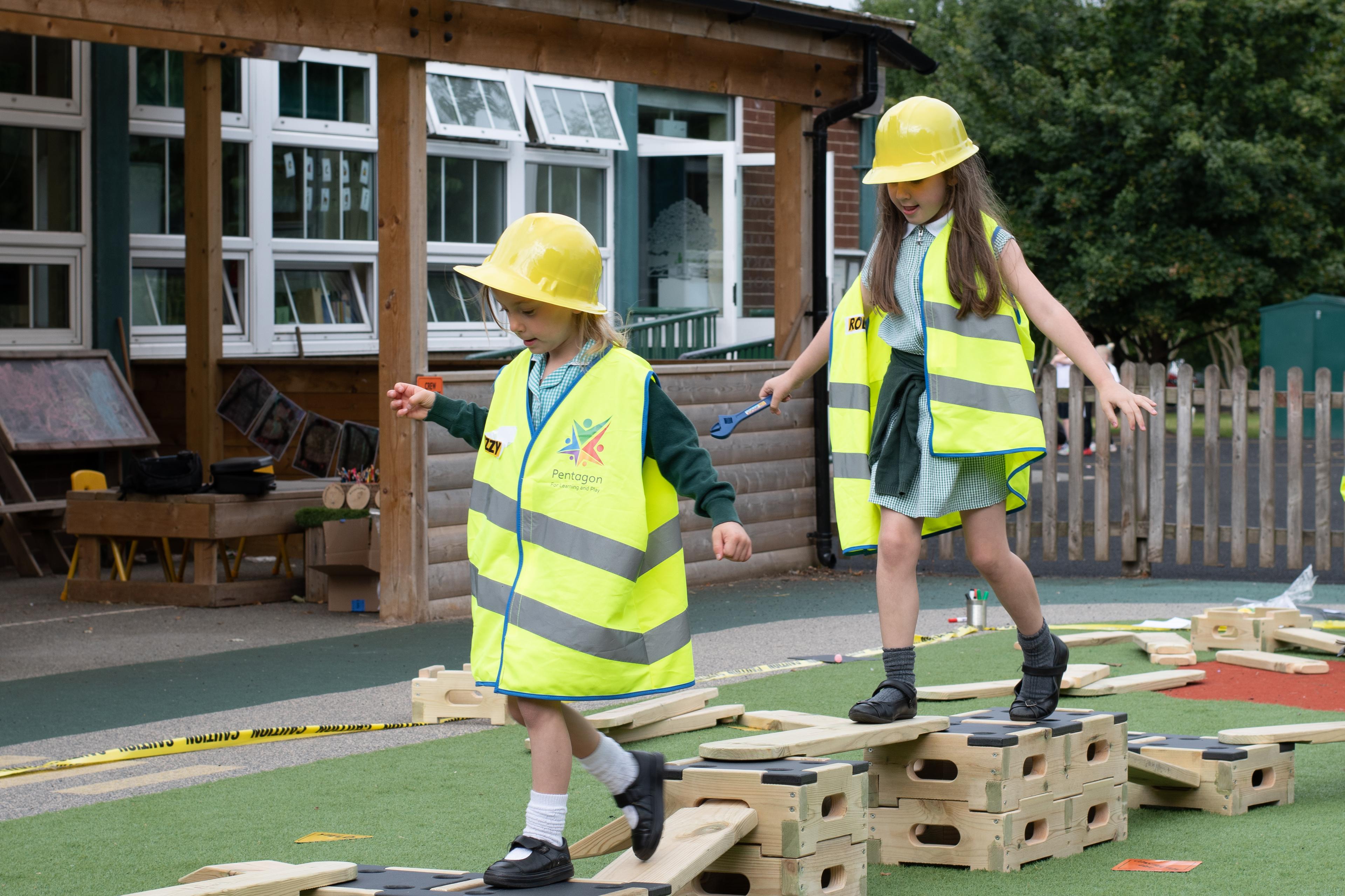 Two children walking along the trail that they have made with the play builder set