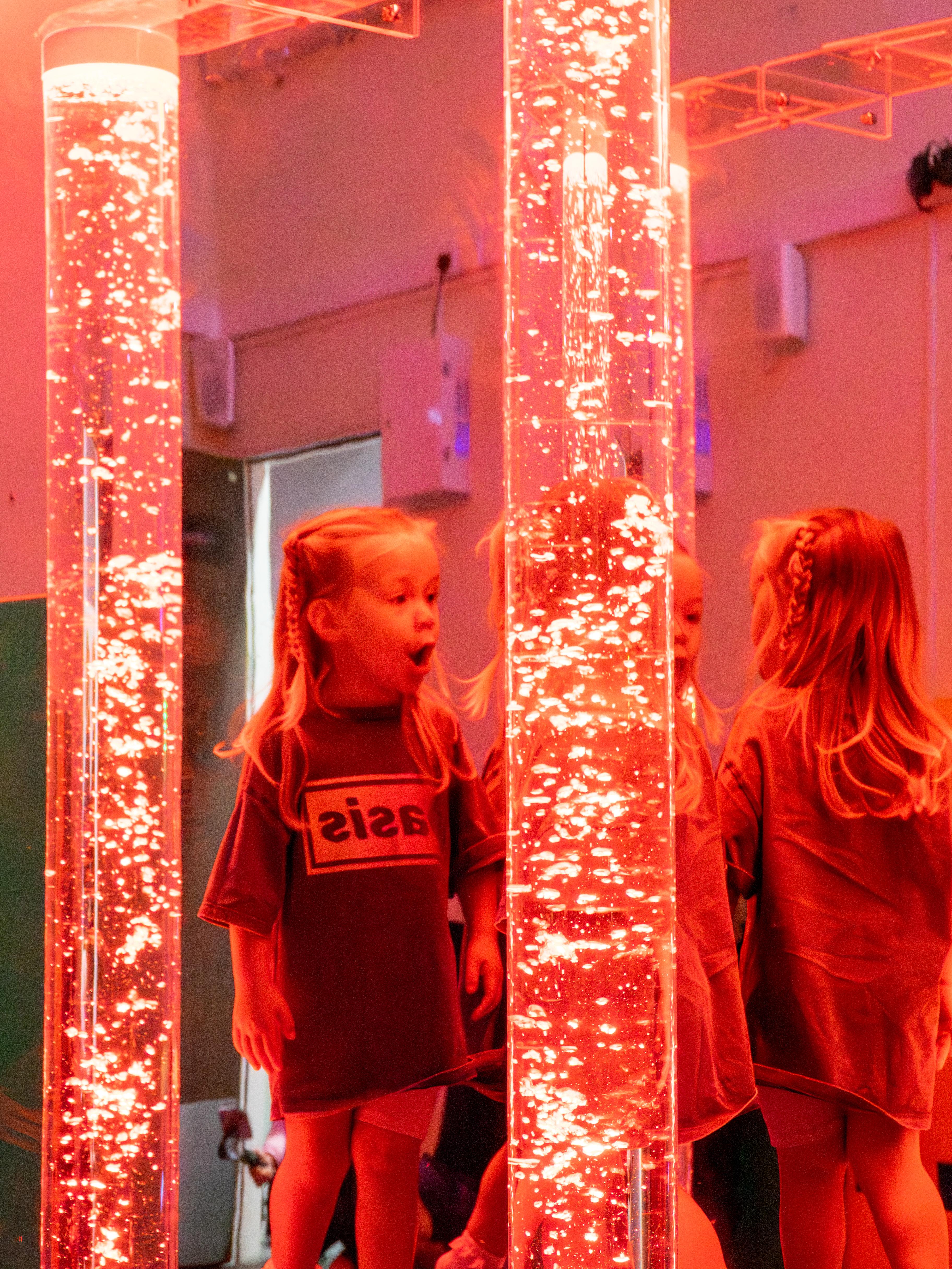 Two young girls playing with a light up sensory bubble tube.