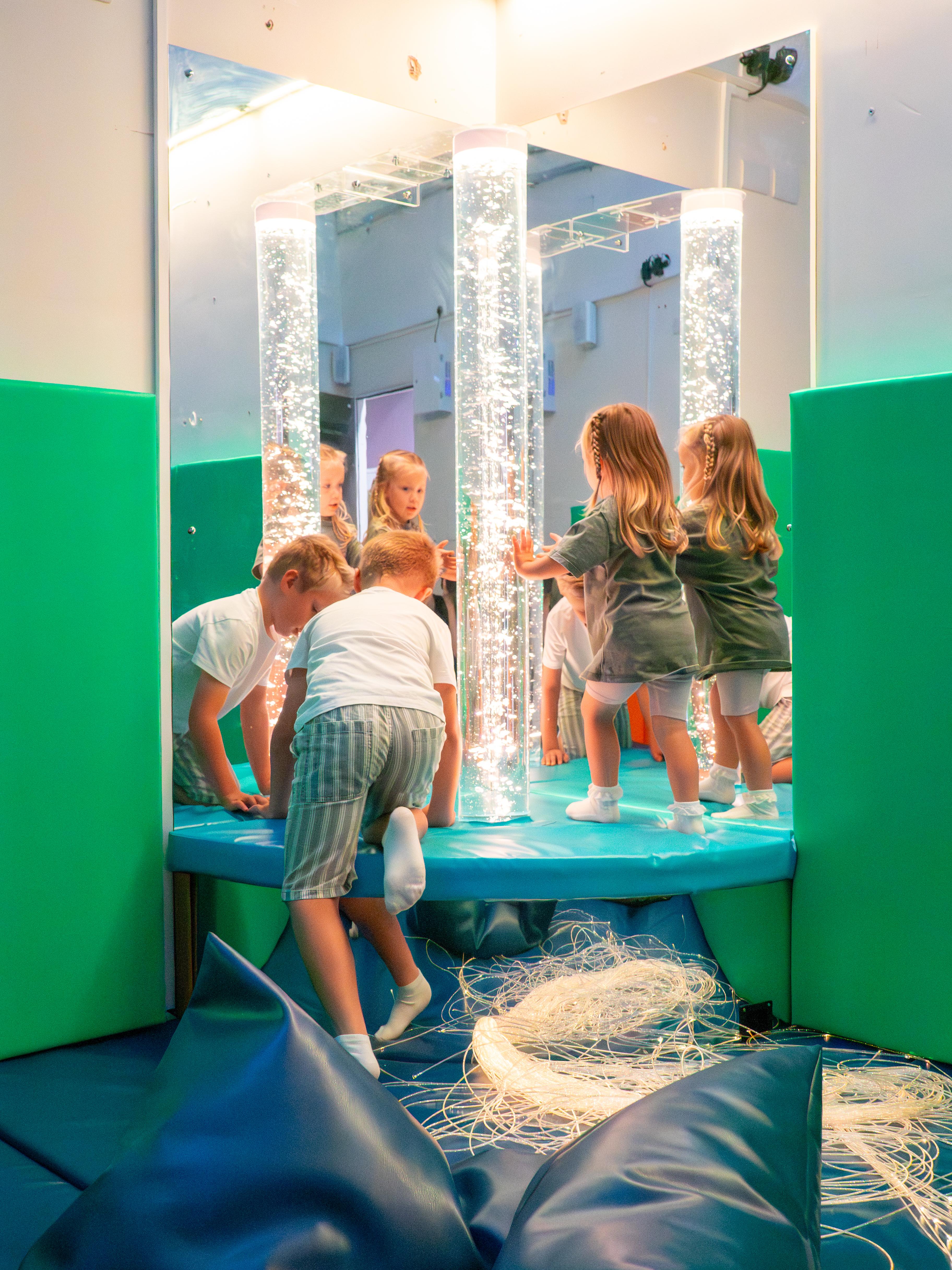 Two children playing with a light up sensory bubble tube.