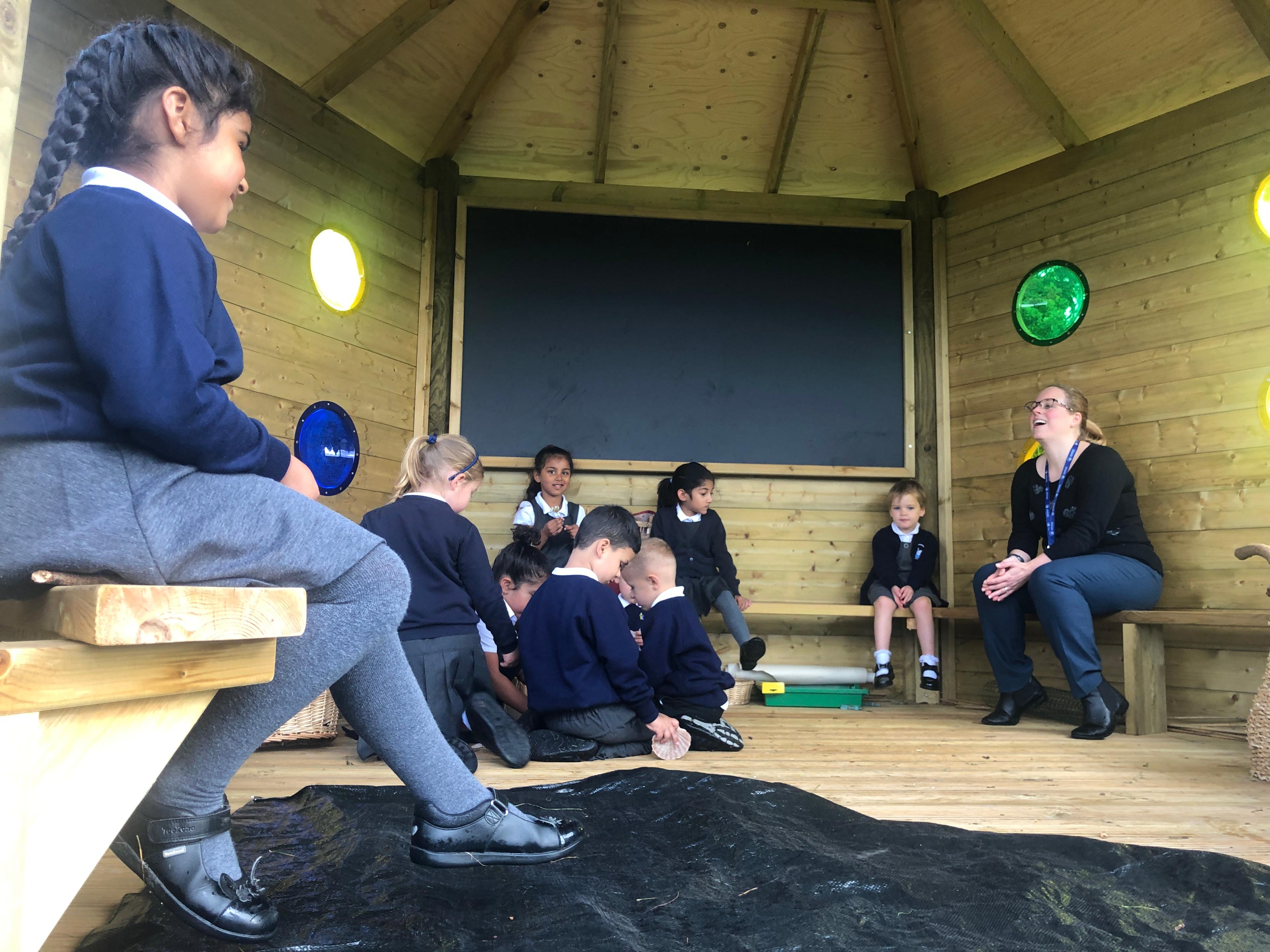 Children sat on the benches inside of the Sensory 5M Hexagonal Gazebo