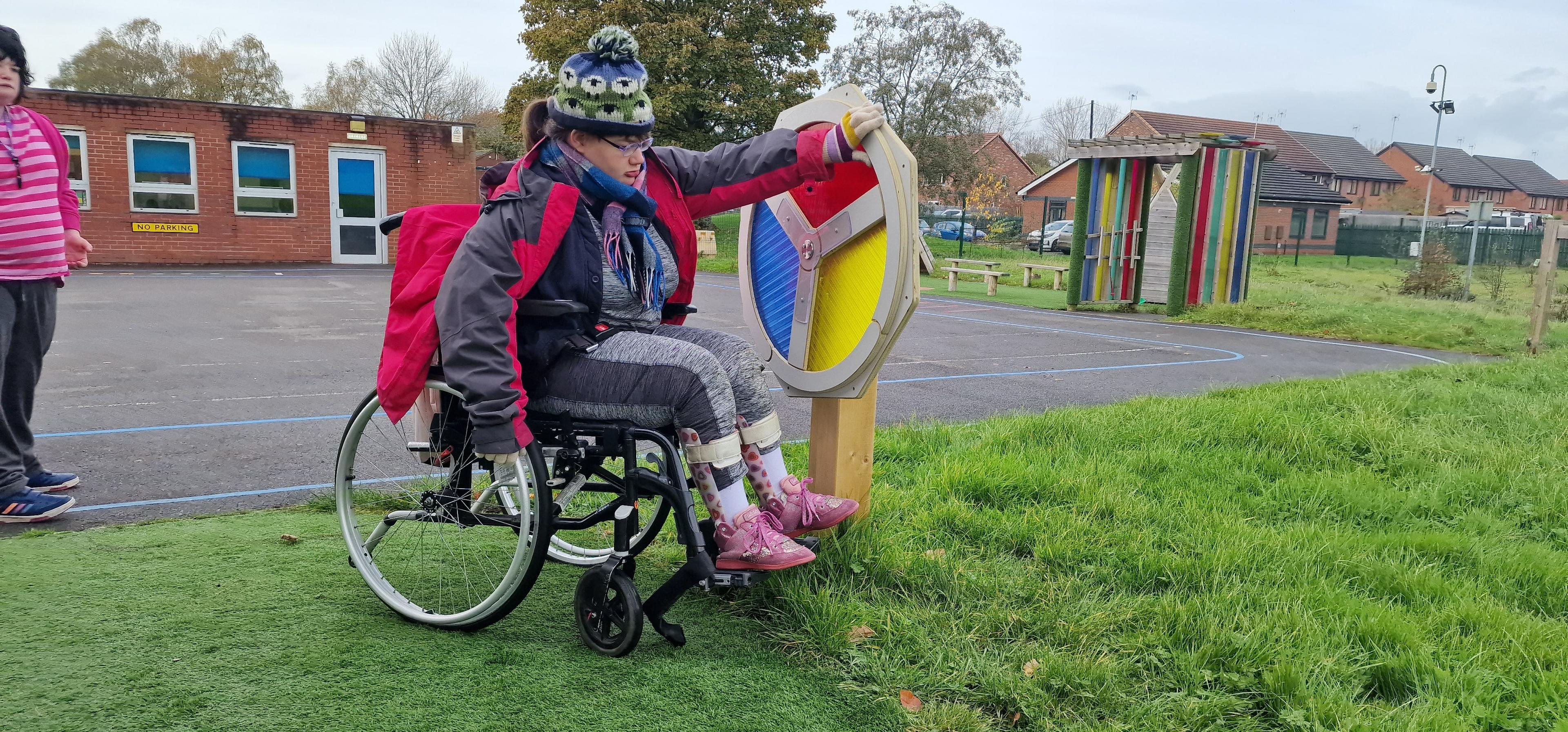 A girl in a wheelchair is grabbing the Light Sensory Spinner and is spinning it.