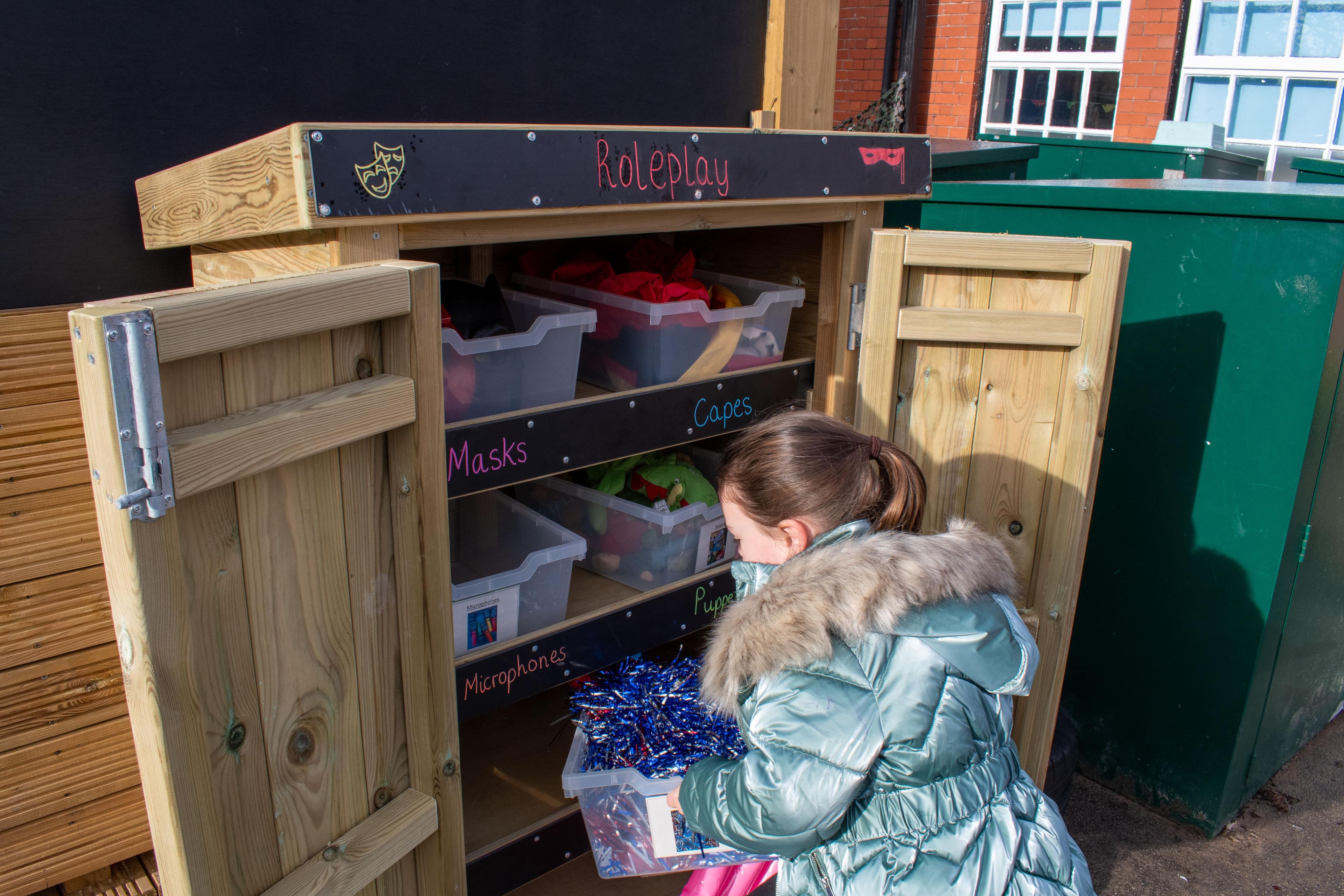 Young school child getting resources out of a Wooden Acorn Storage Unit in a school playground