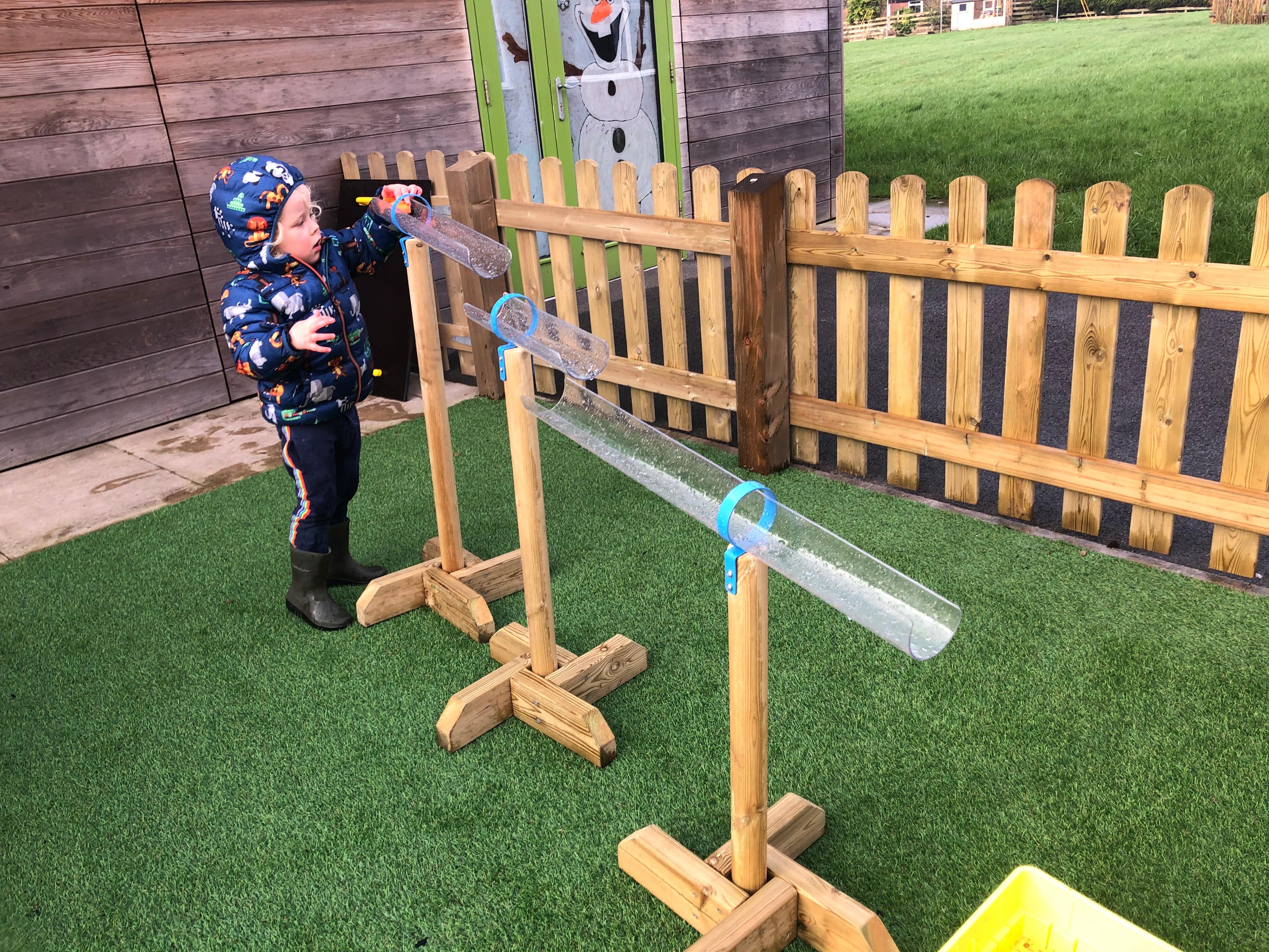 A little boy is stood at the beginning of the Water Channel Stands with a toy car, wanting to drive it through the tubes.