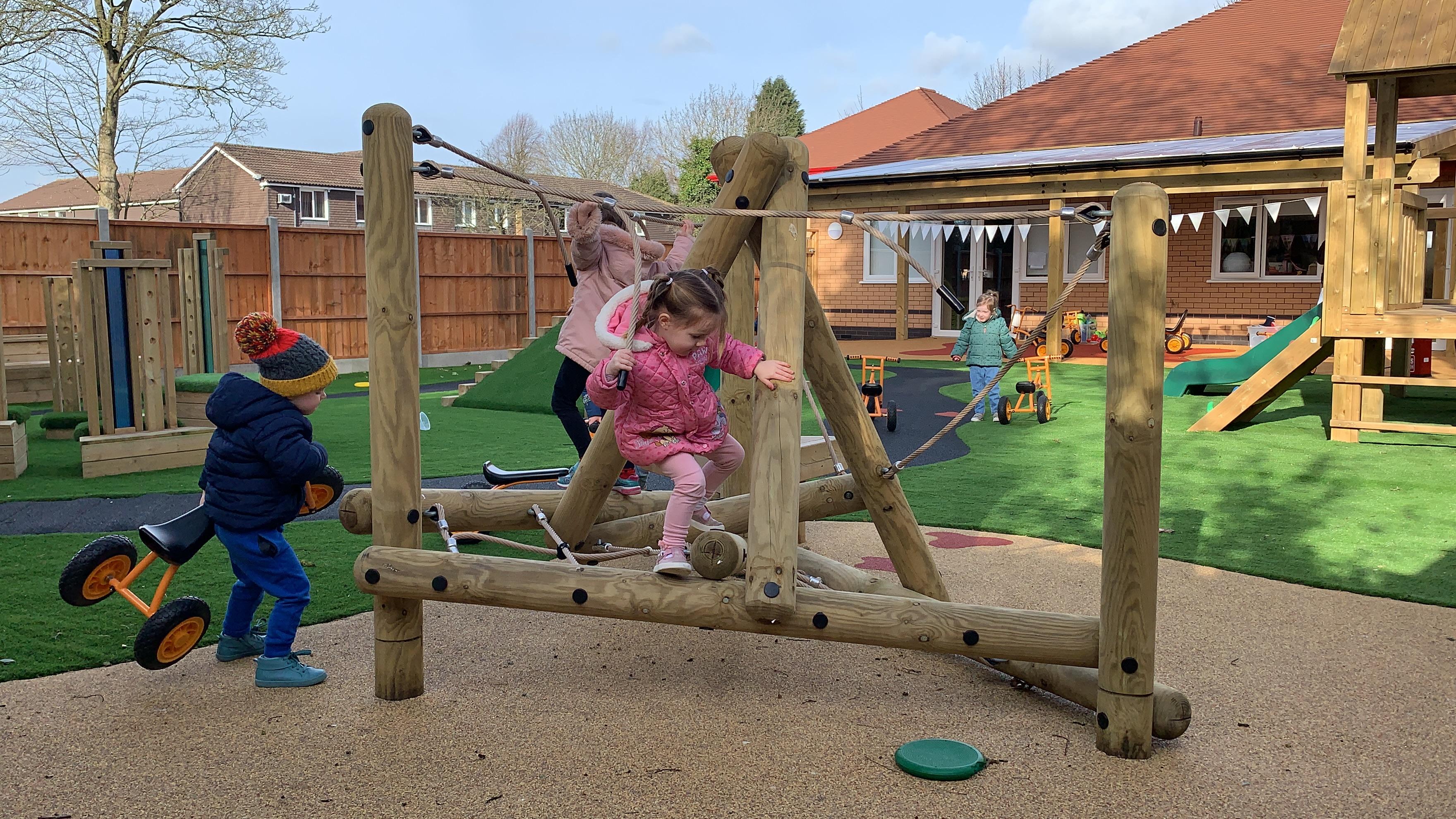 A group of children playing on the Pinnacle Hill Climber with platform in the playground