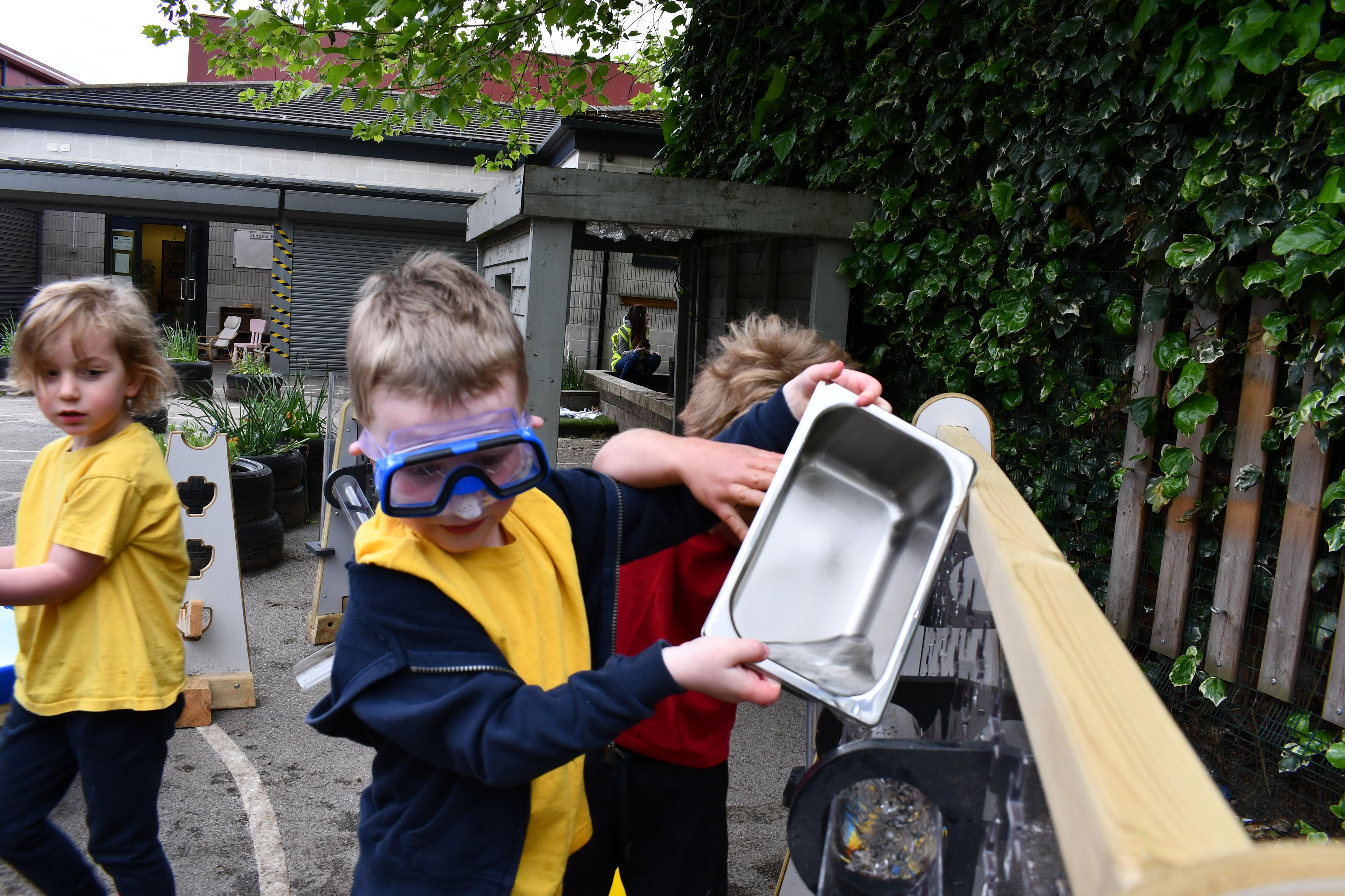 A boy holding a stainless steel pan used to collect water from the water wall