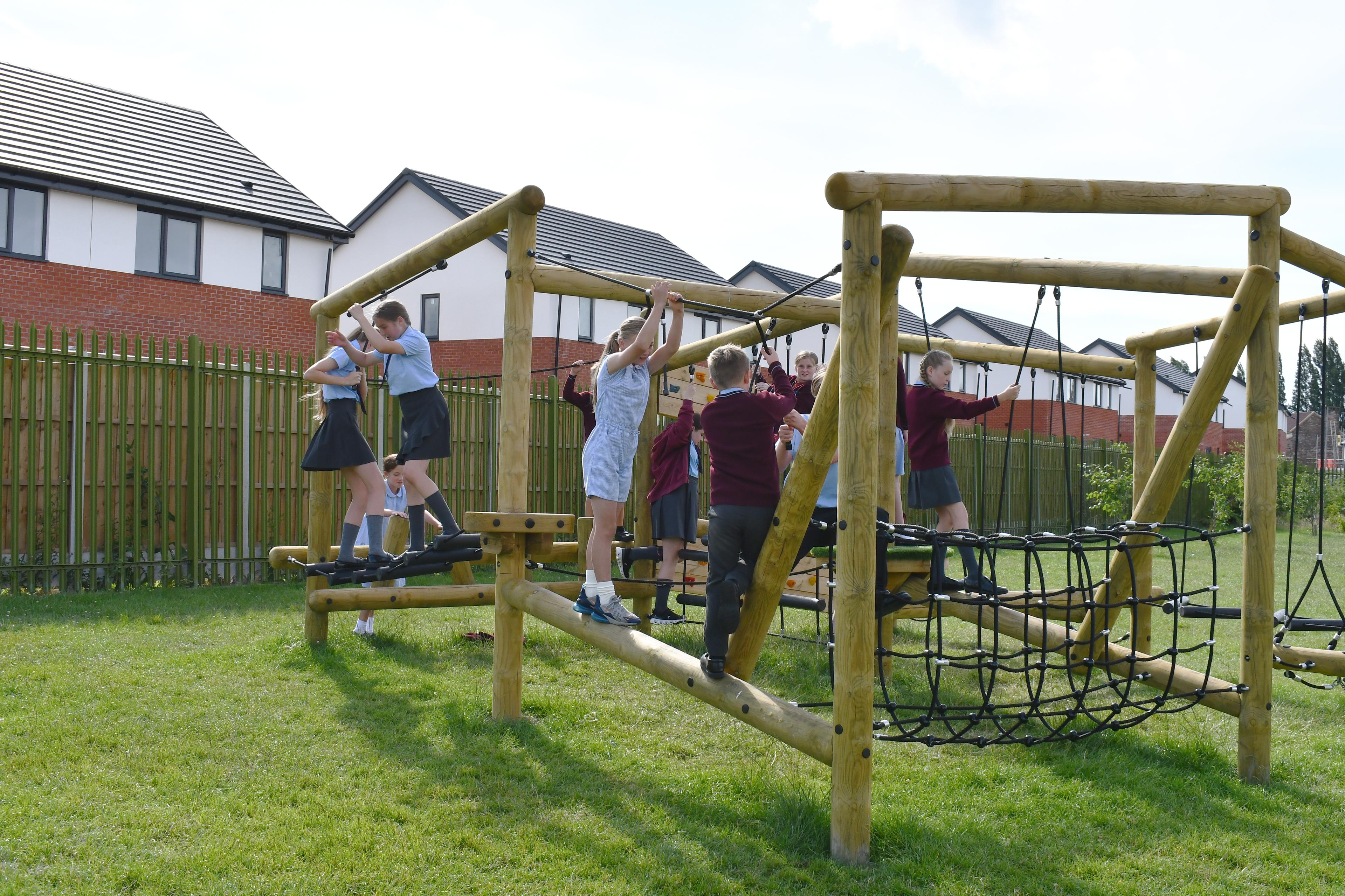 A group of children climbing on a open ended climbing frame for schools