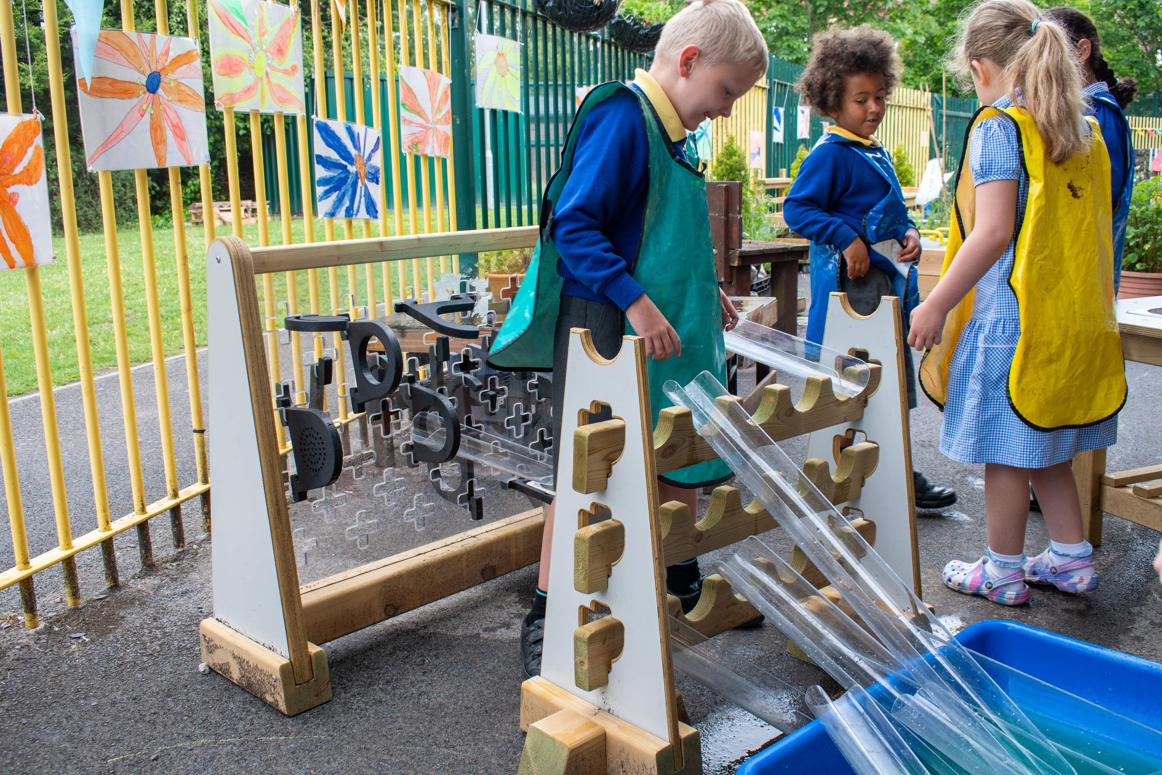 A group of early years children are experimenting with water by using the early years water channel stands.