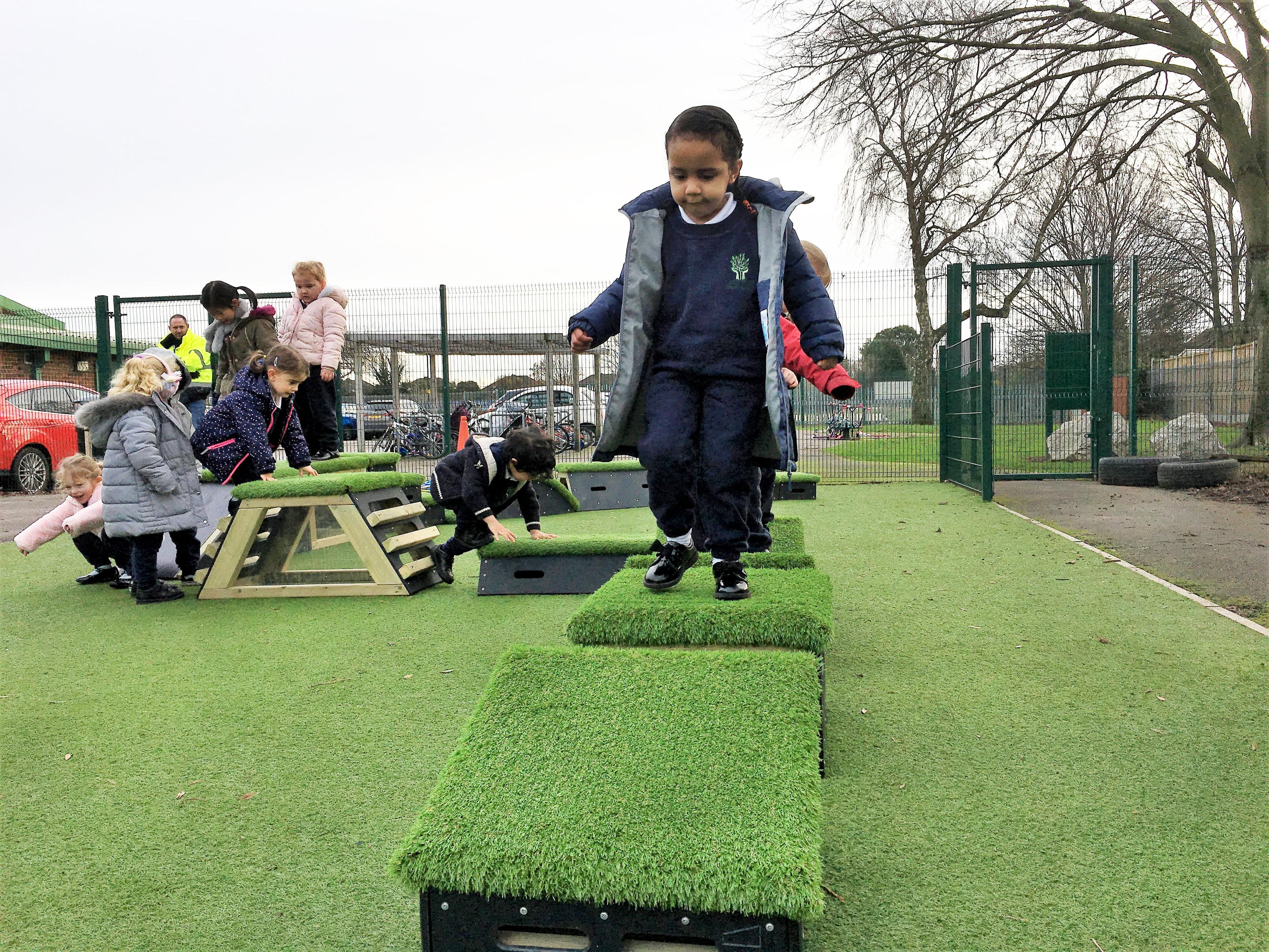 A boy jumping across grass topped blocks