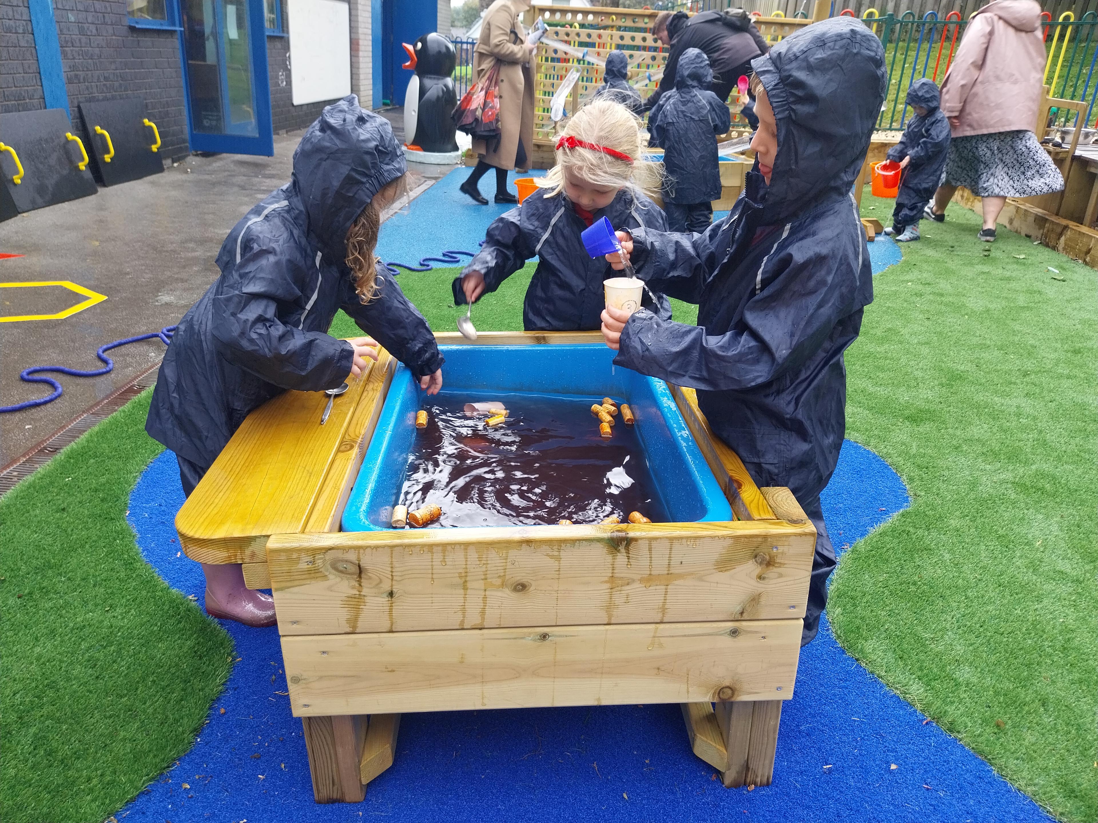 A group of children playing with water in the water table