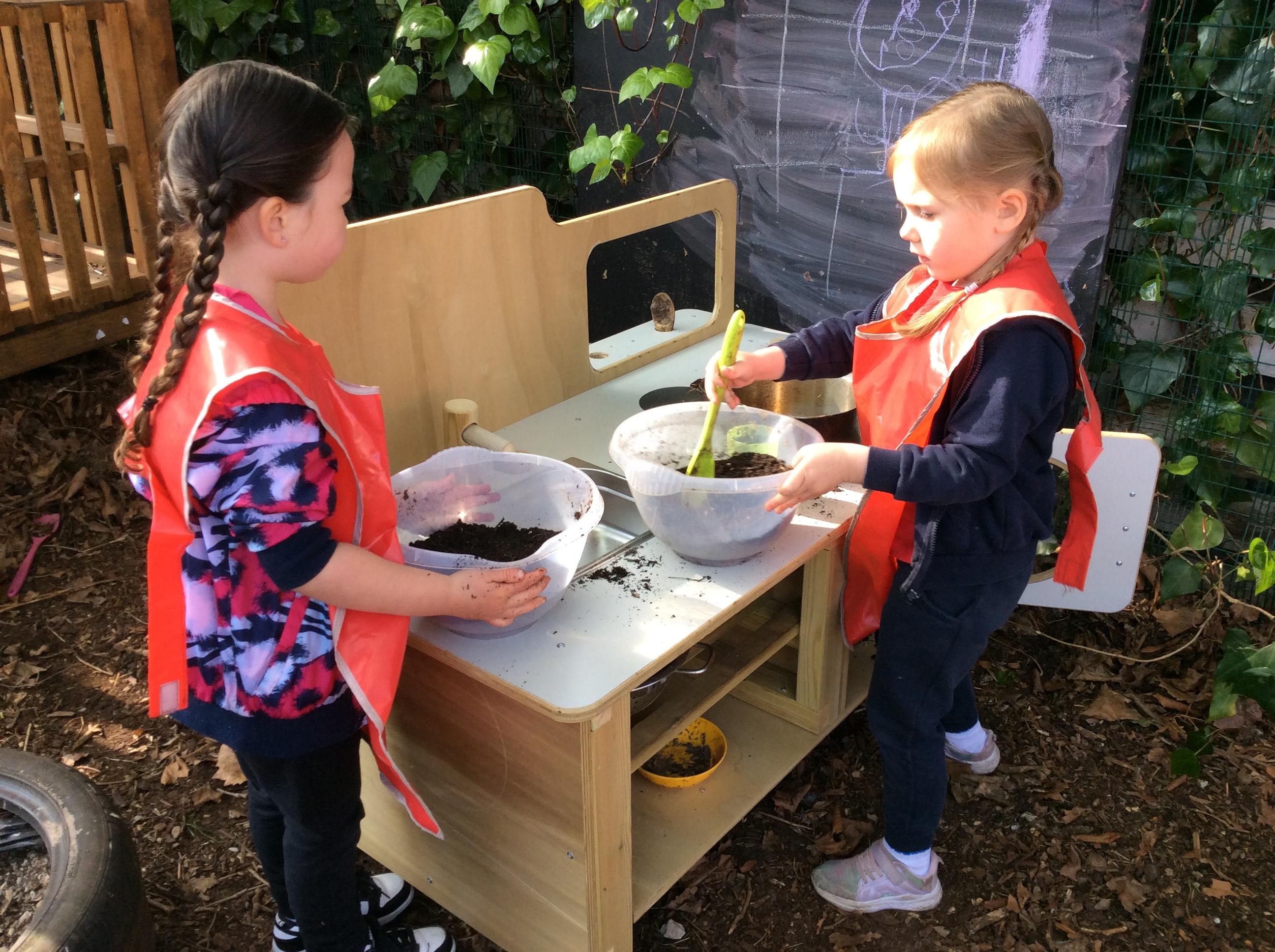 Children playing with the mud kitchen with oven that makes up part of the Pioneer Messy Play Package
