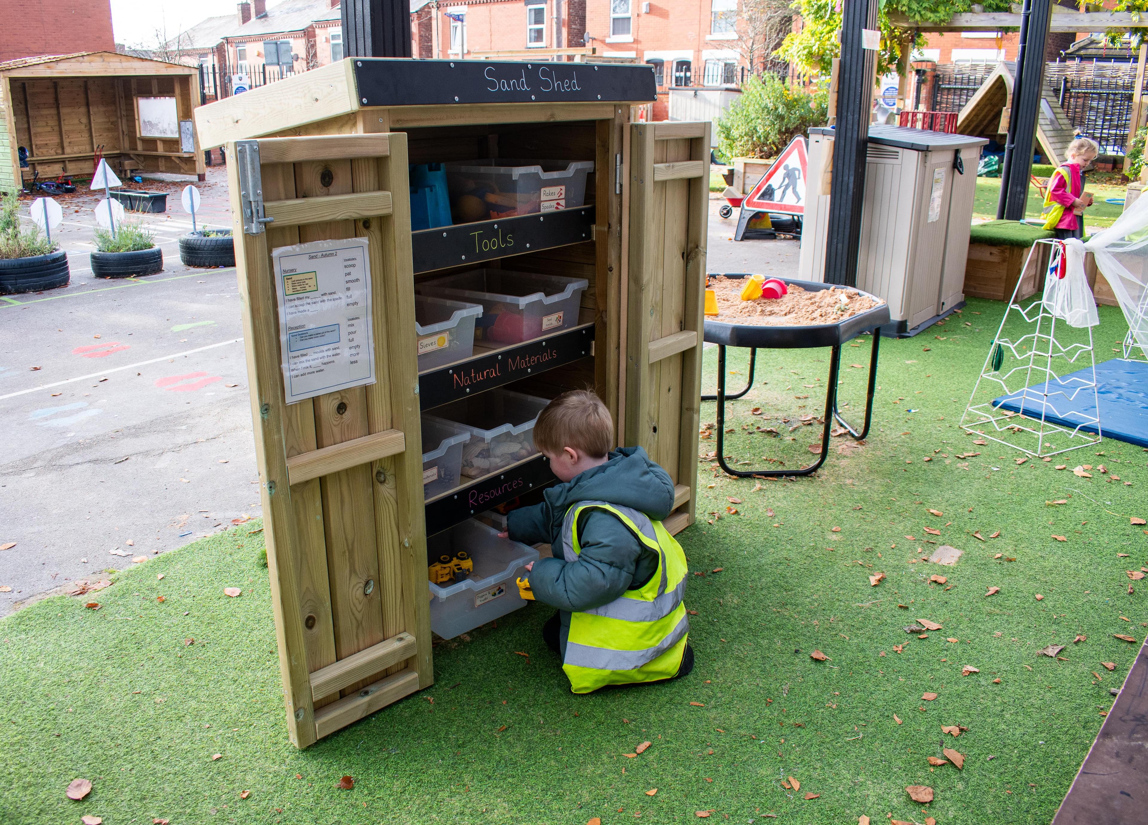 Young school child getting resources out of a Wooden Acorn Storage Unit in a school playground