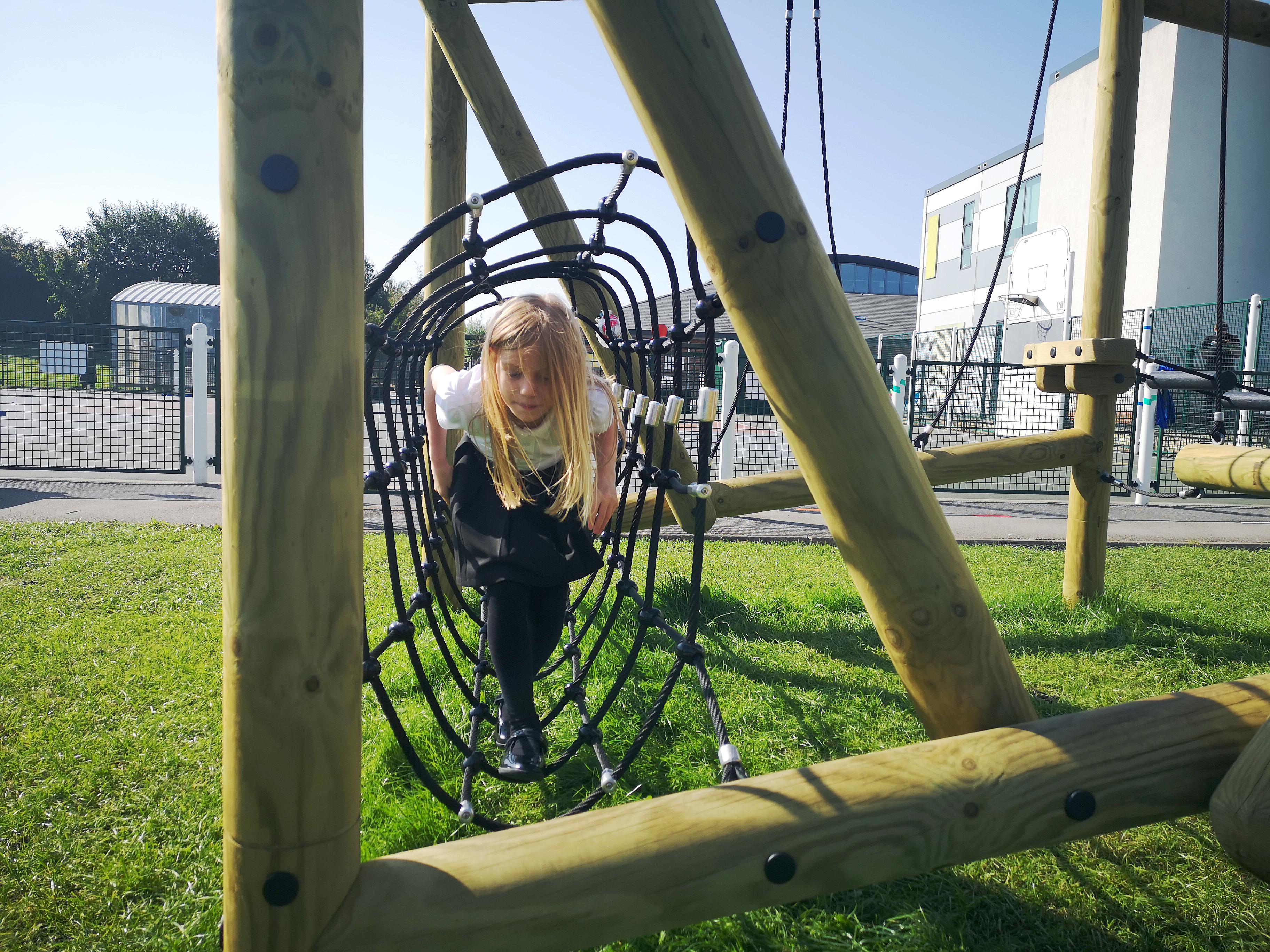 Young girl crawling through the net tunnel on the Puzzlewood Forest Circuit