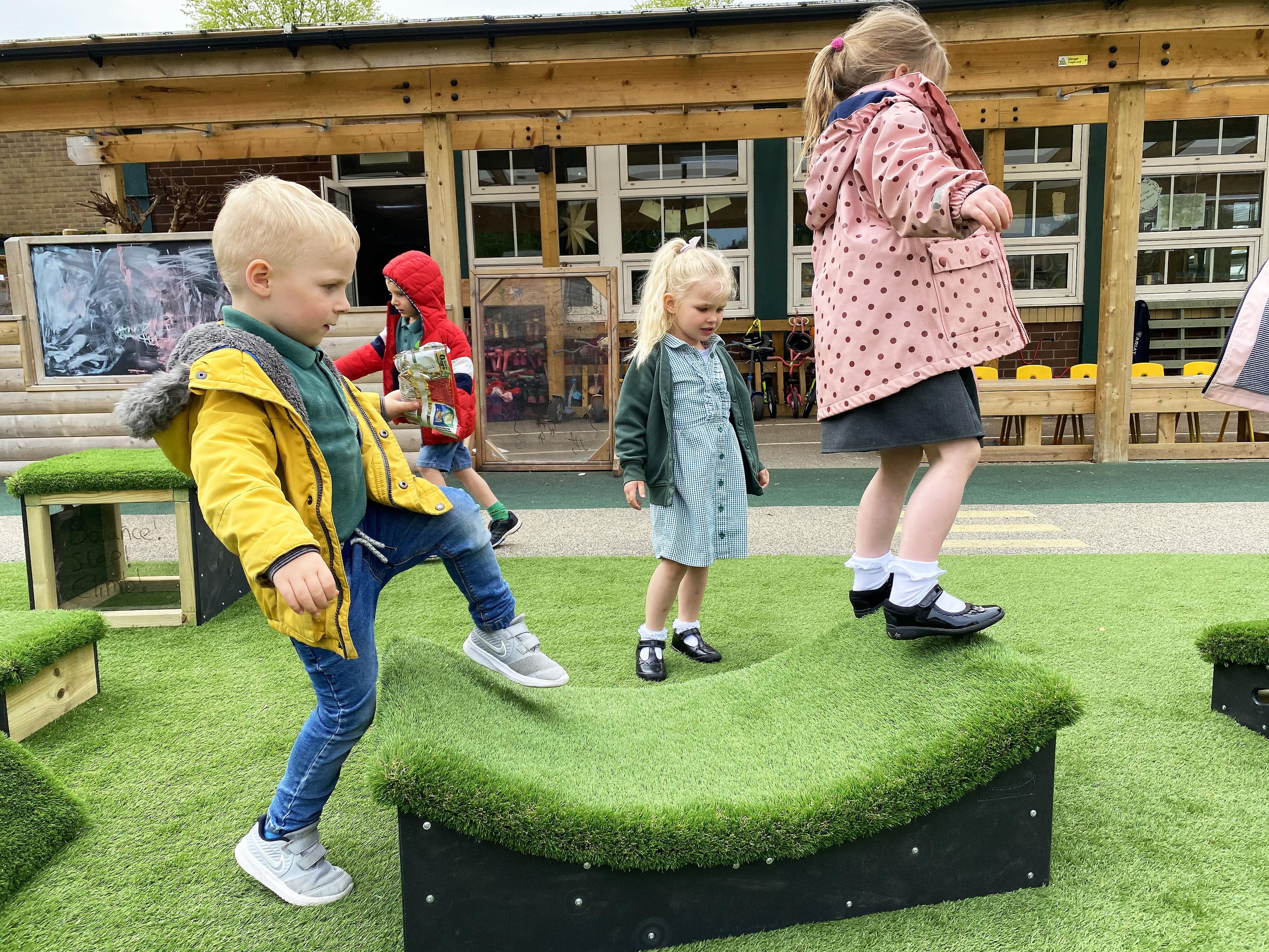 A young boy stepping onto a block and young girl balancing off the edge of the block