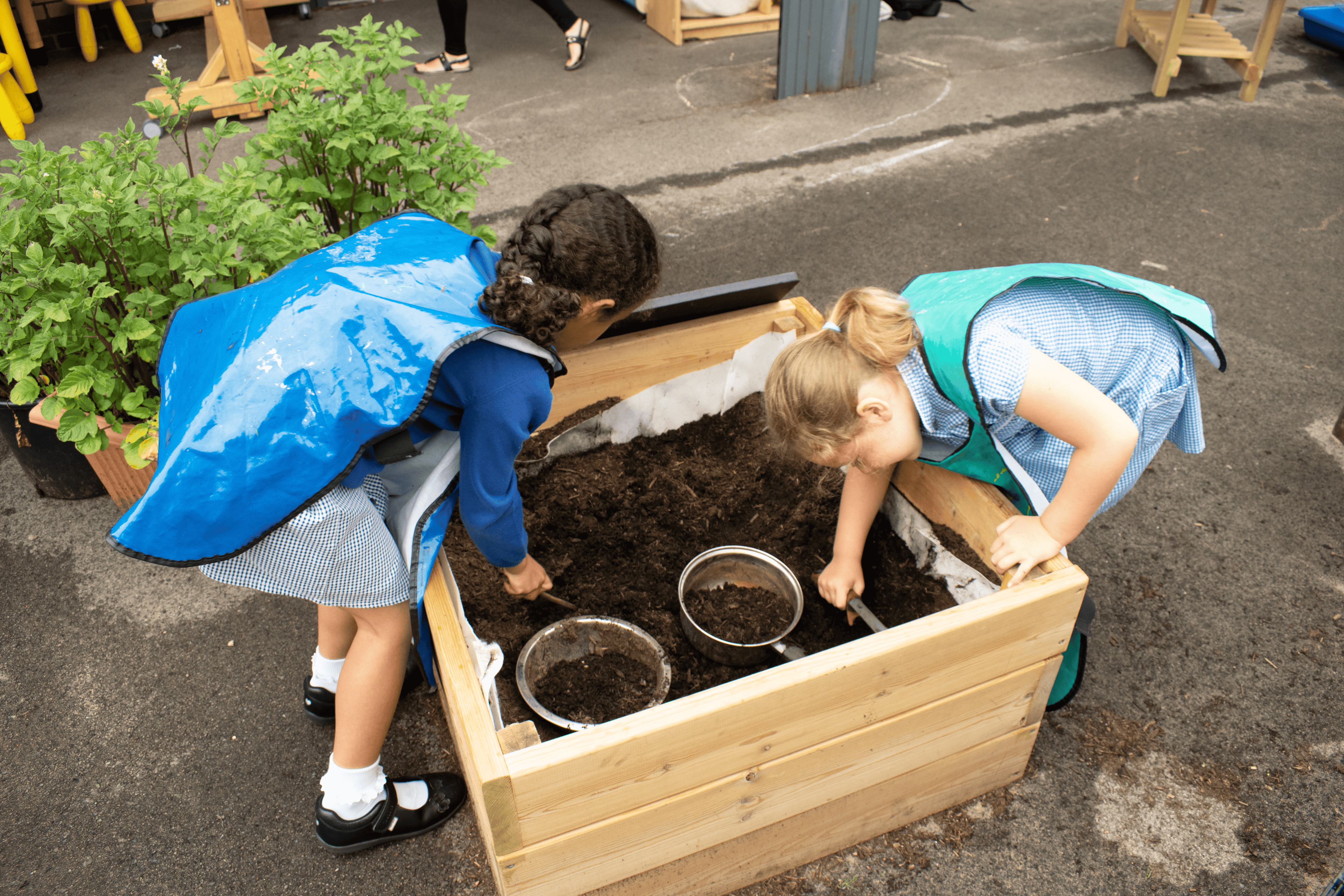 Two little girls are digging through the mud with some tools.