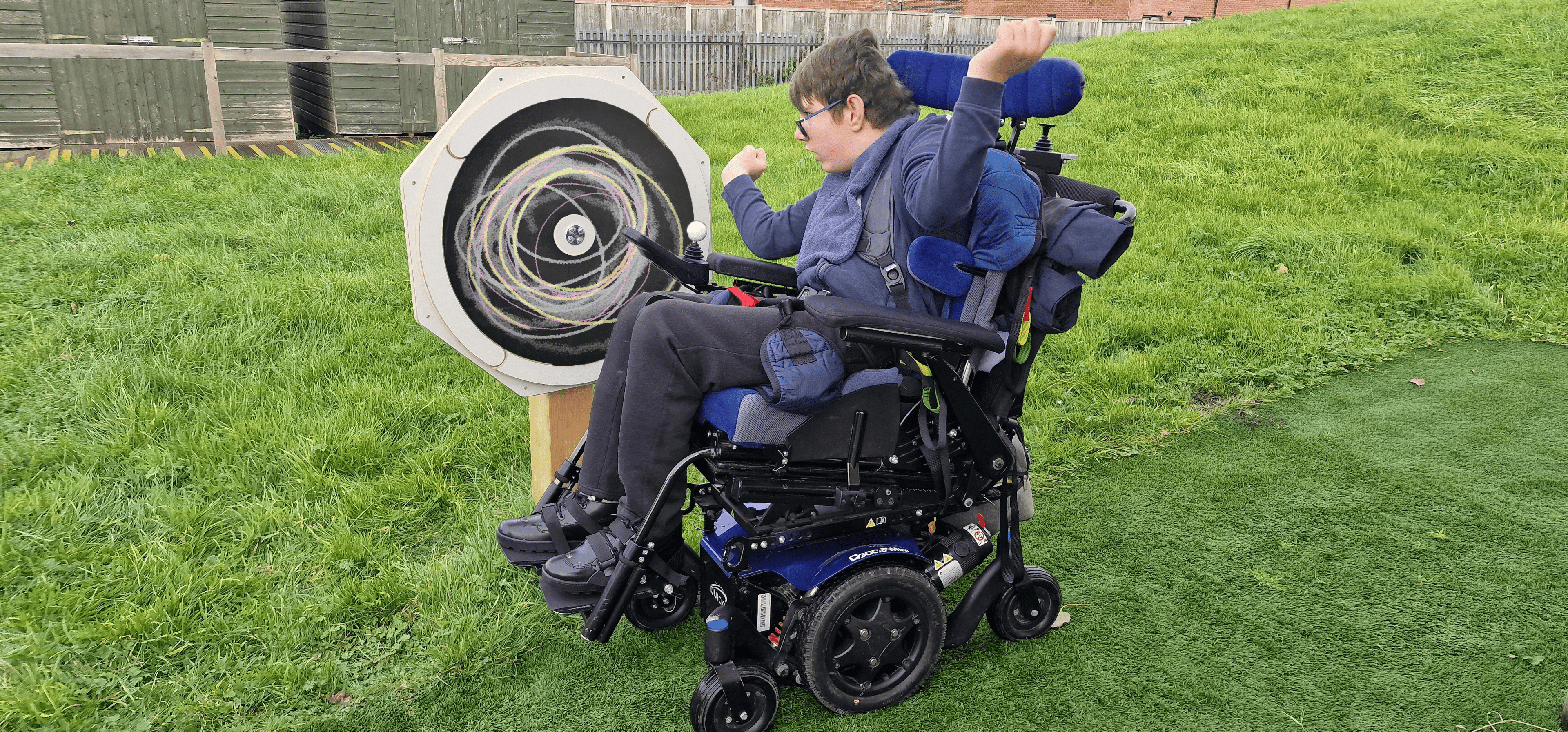 A boy in a wheel chair is looking at the Drawing Sensory Spinner.