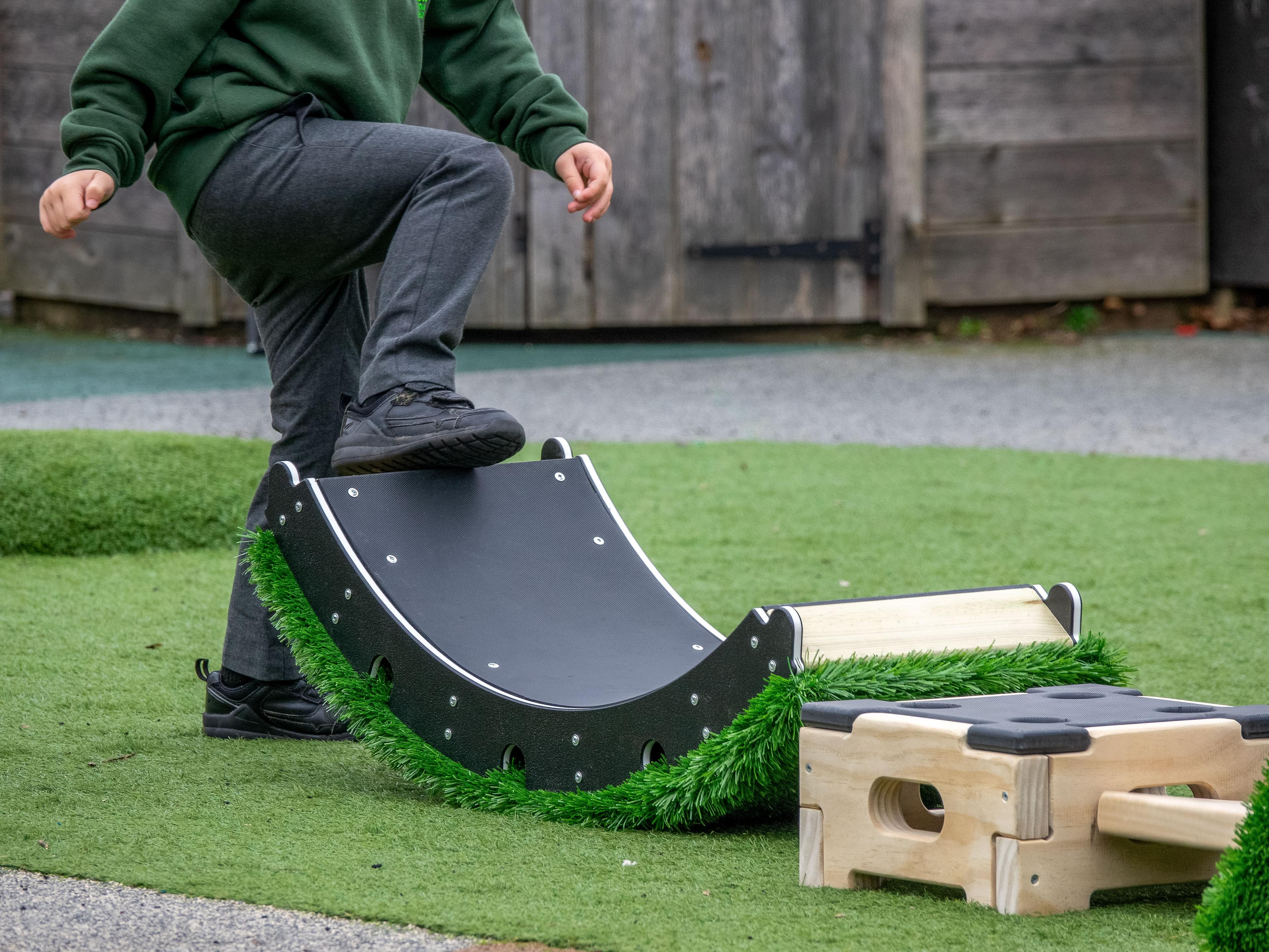 A child has one foot resting on the curved part of the Rockies modular block.