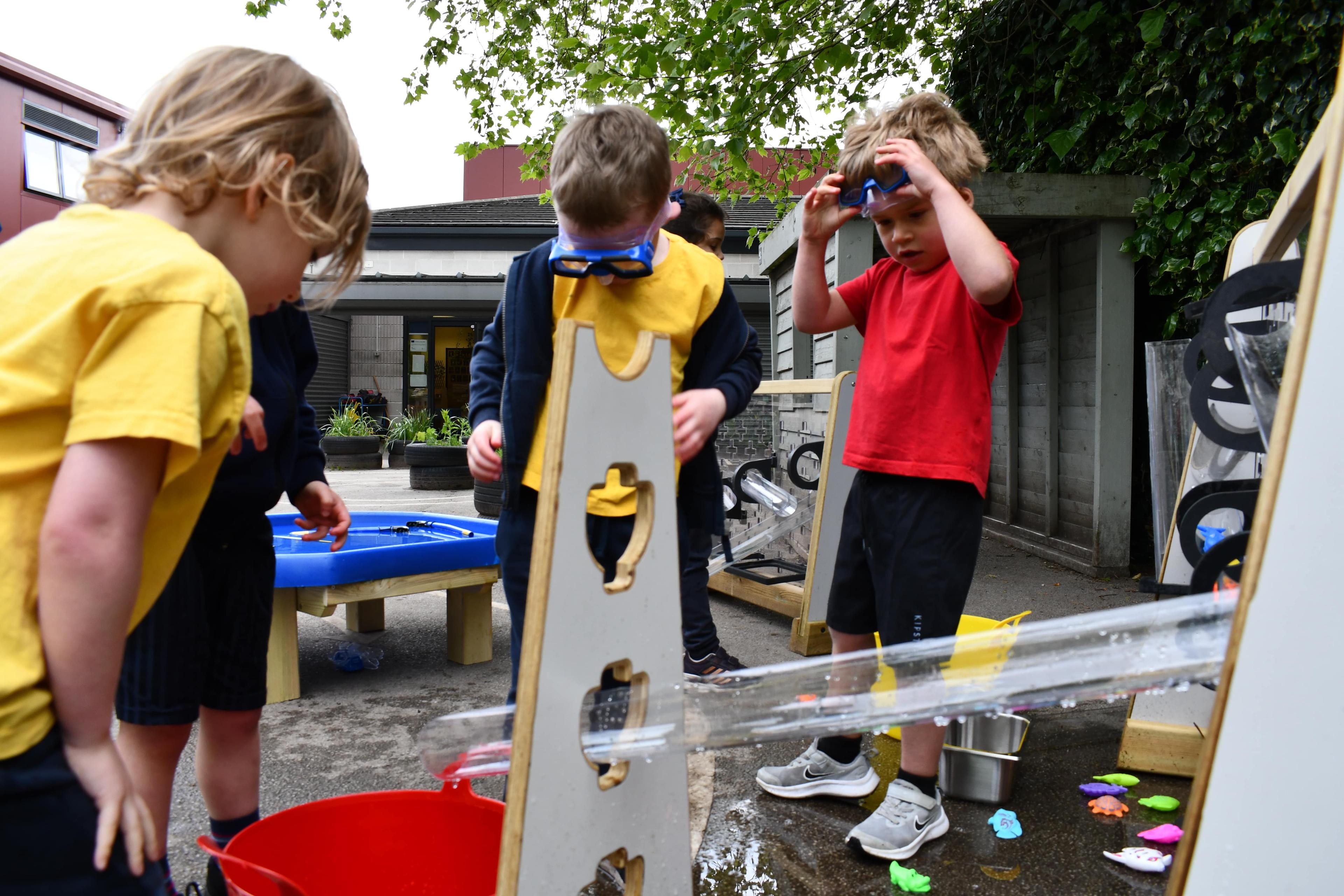 Four children are wearing goggles as they experiment with water on their equipment.