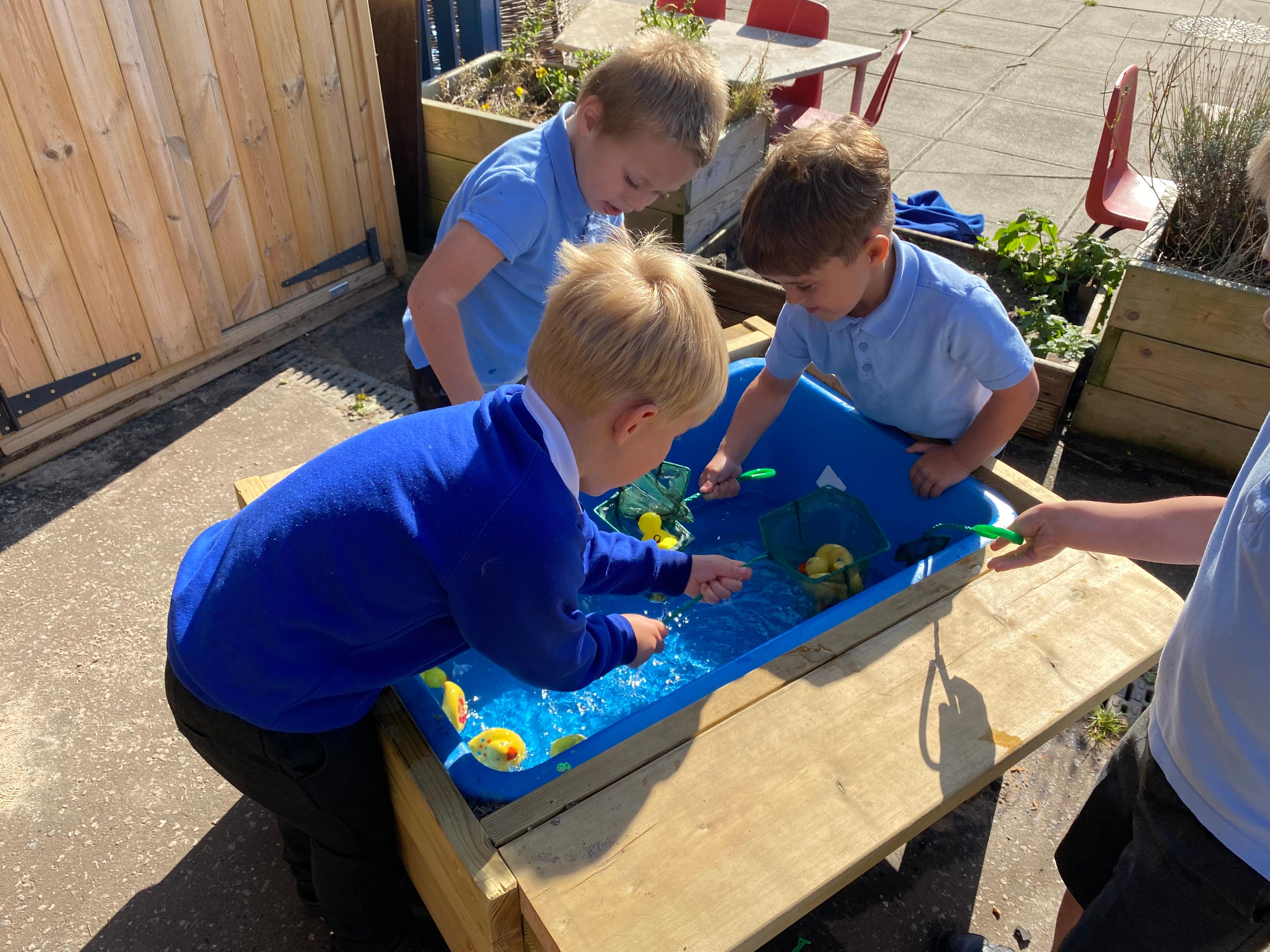 A group of children playing with water in the water table