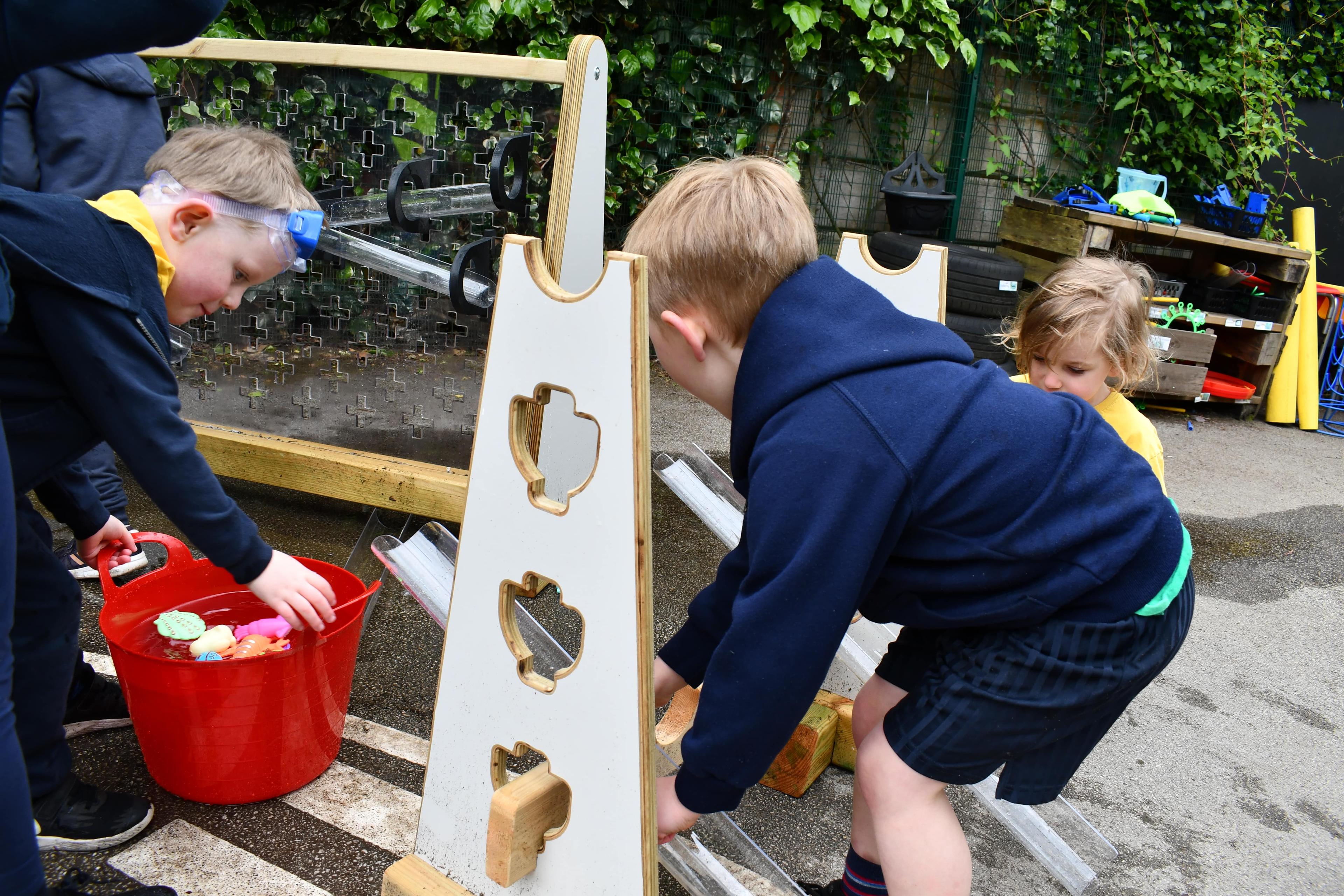 Early years children are constructing a pathway for water to run down.
