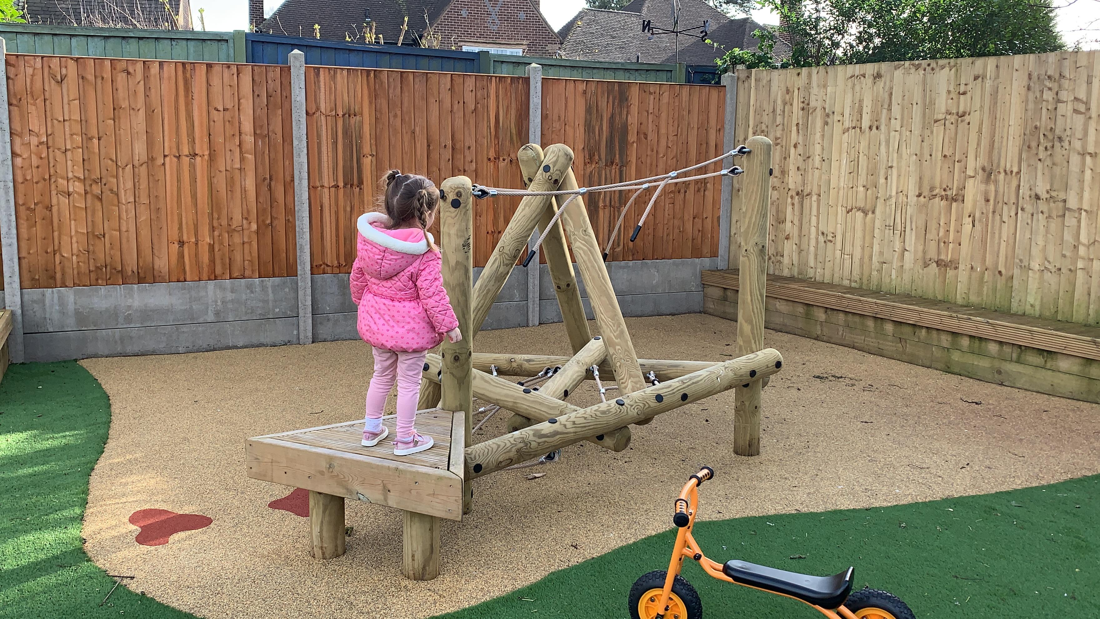 A young girl standing on the platform of the on the Pinnacle Hill Climber in the playground