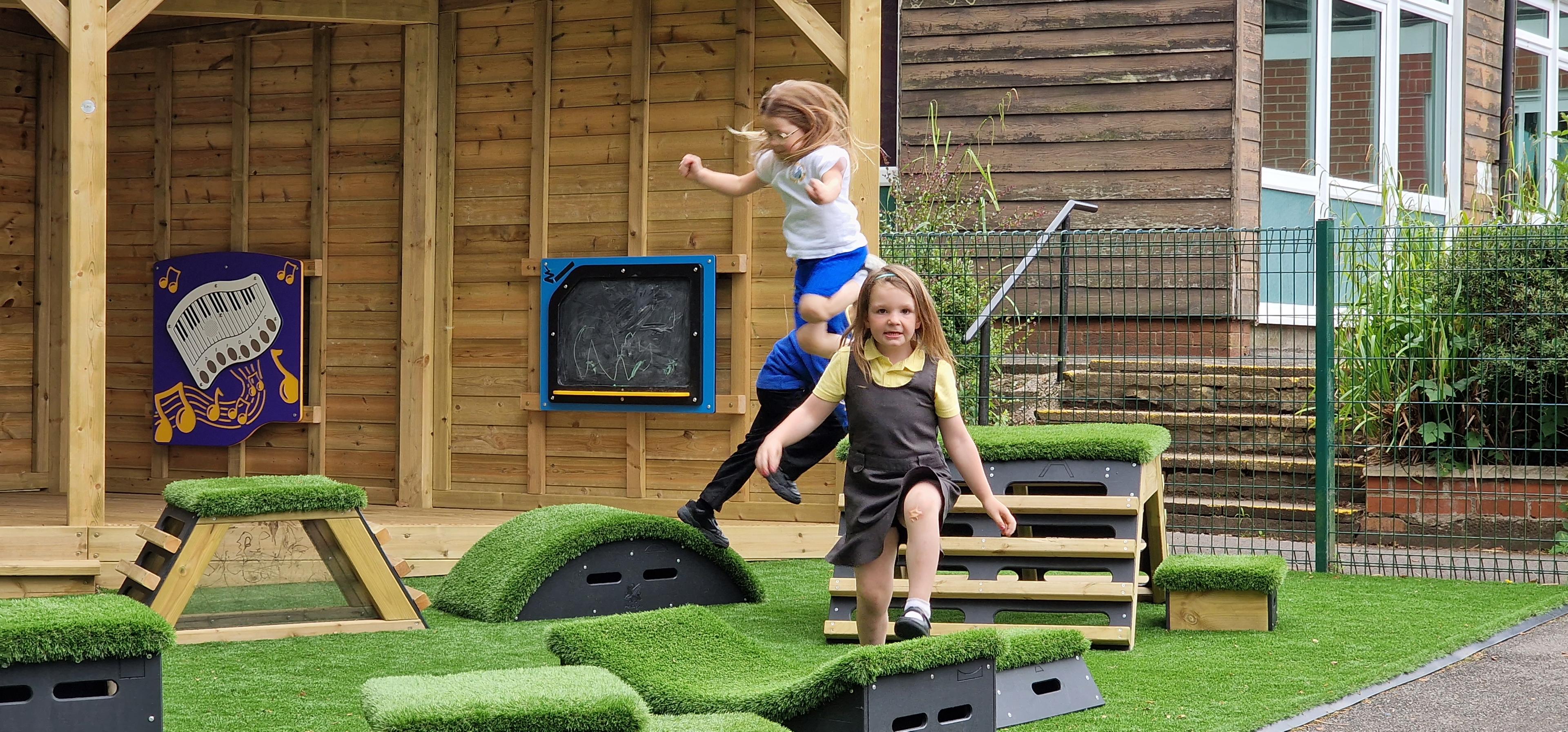 A few children are going across an obstacle course made from Get Set Go Blocks as one of them looks into the camera smiling.