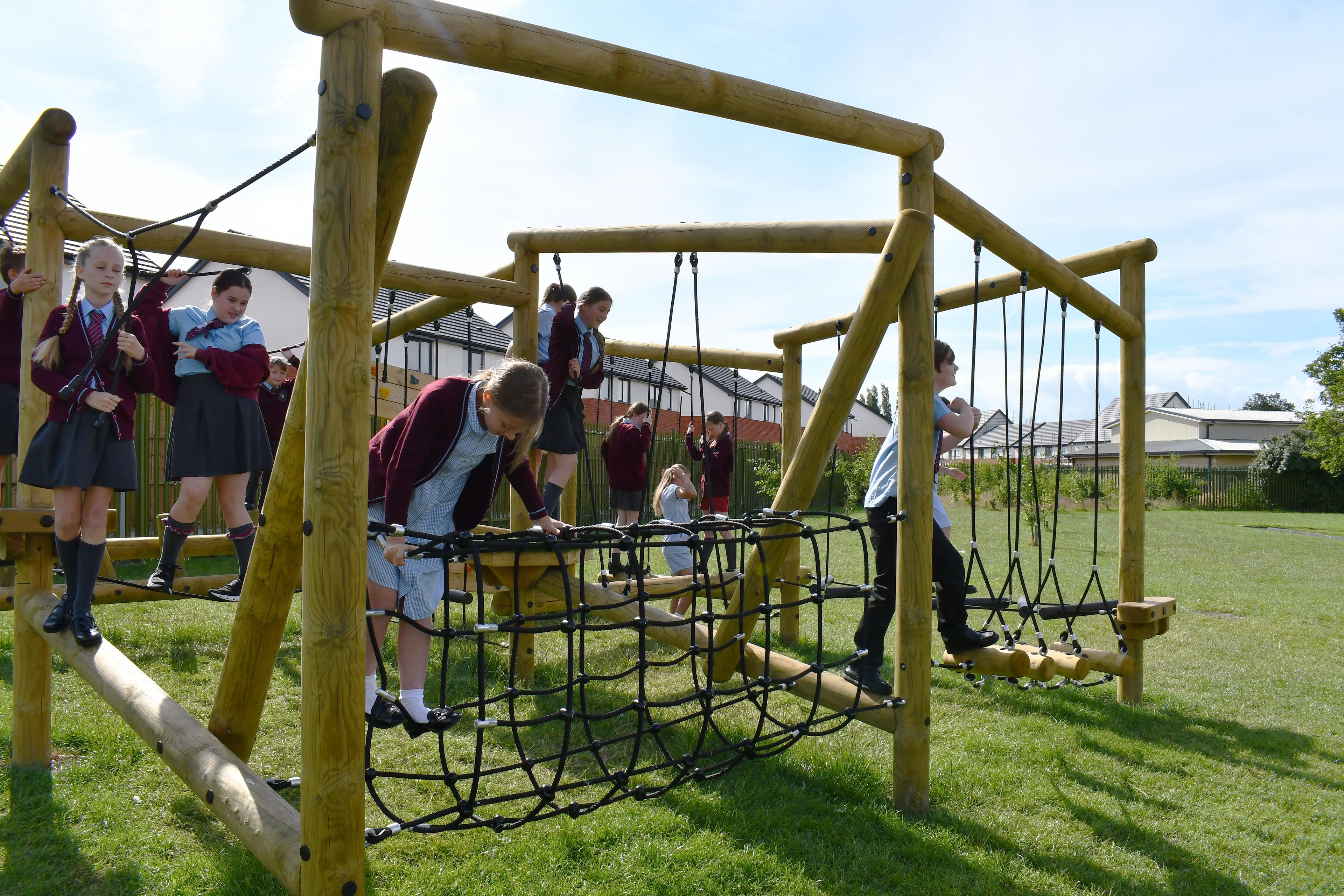 Children playing on an open ended climbing frame in their school