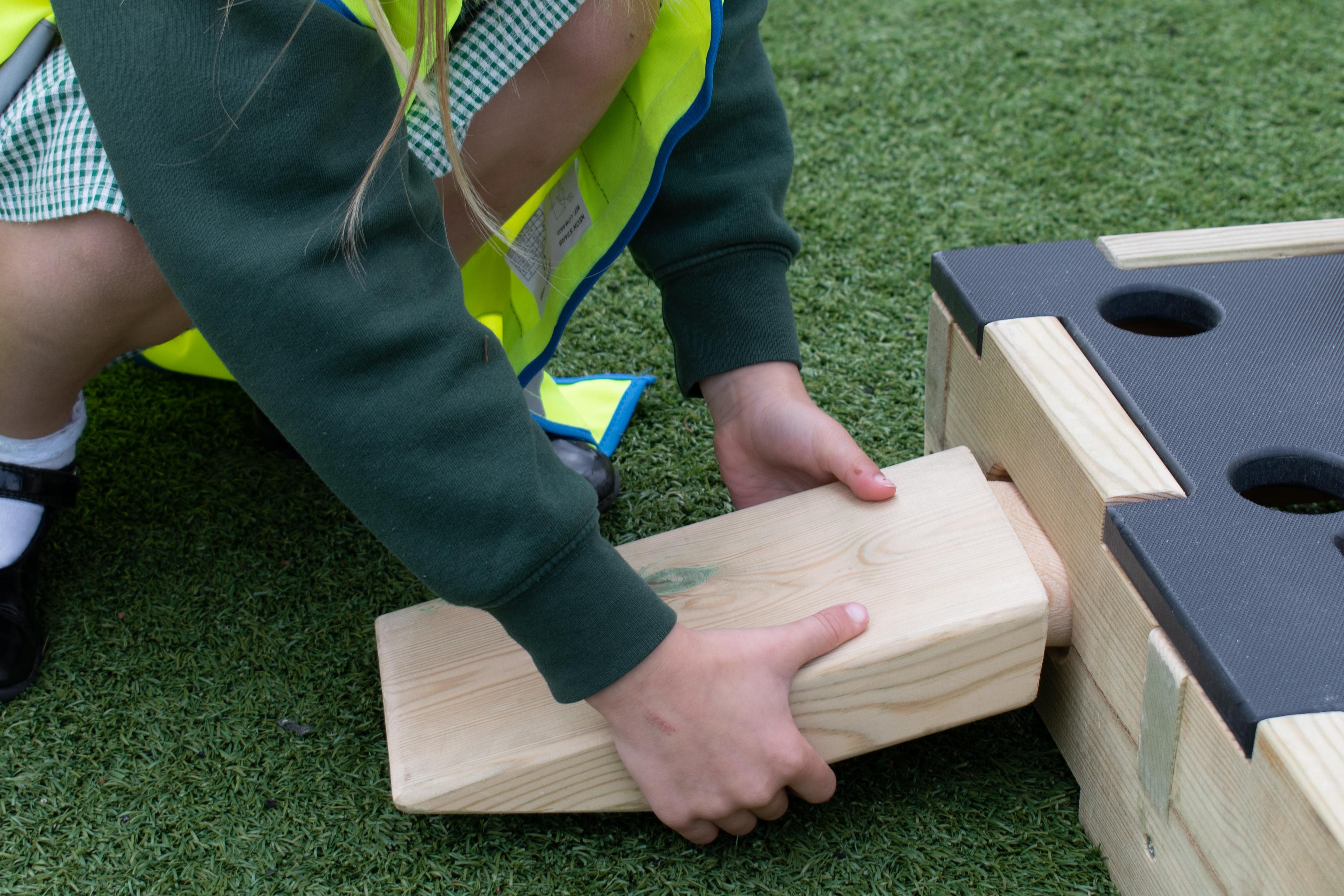 A child connecting a play builder block with a plank