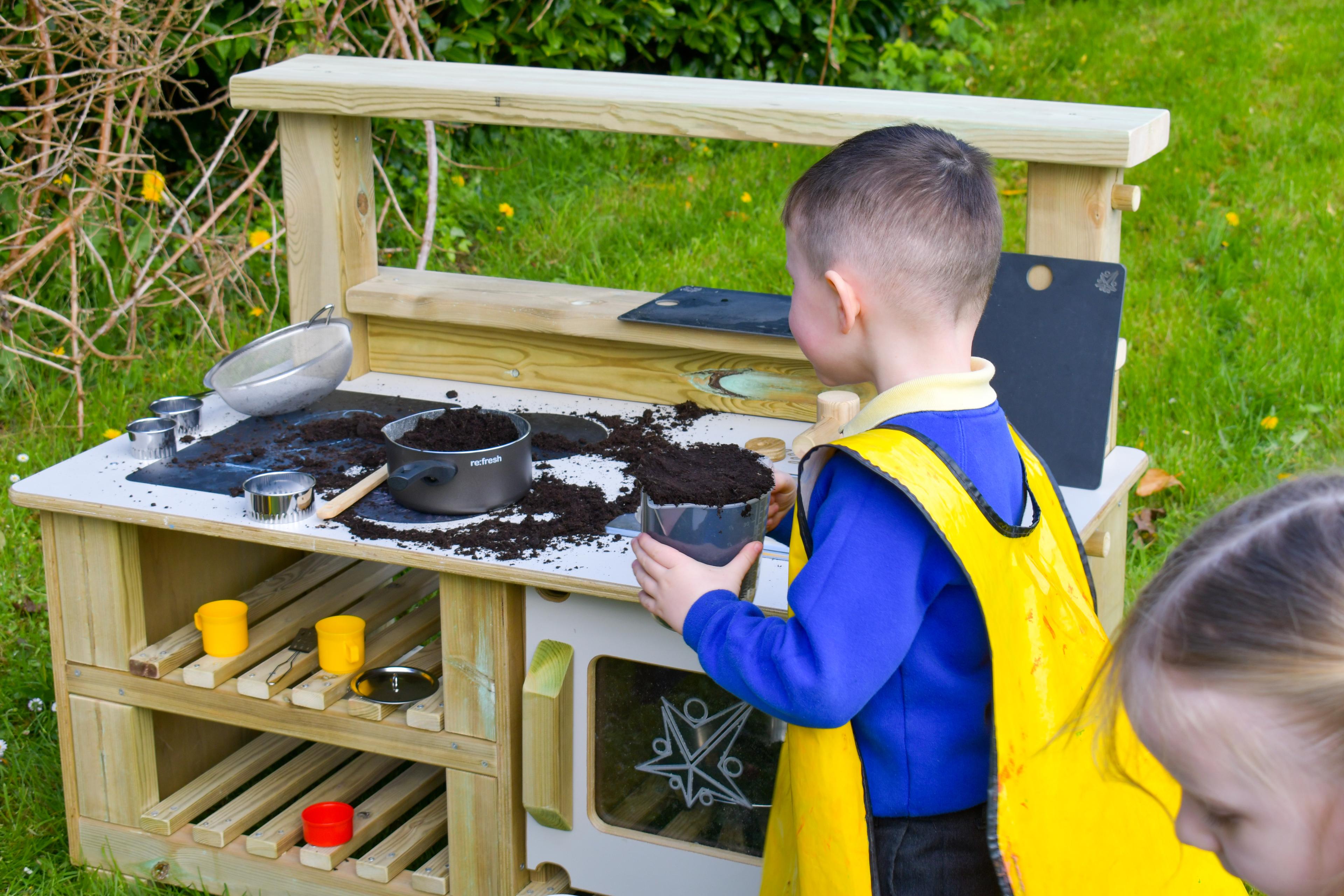 A young boy at the mud kitchen