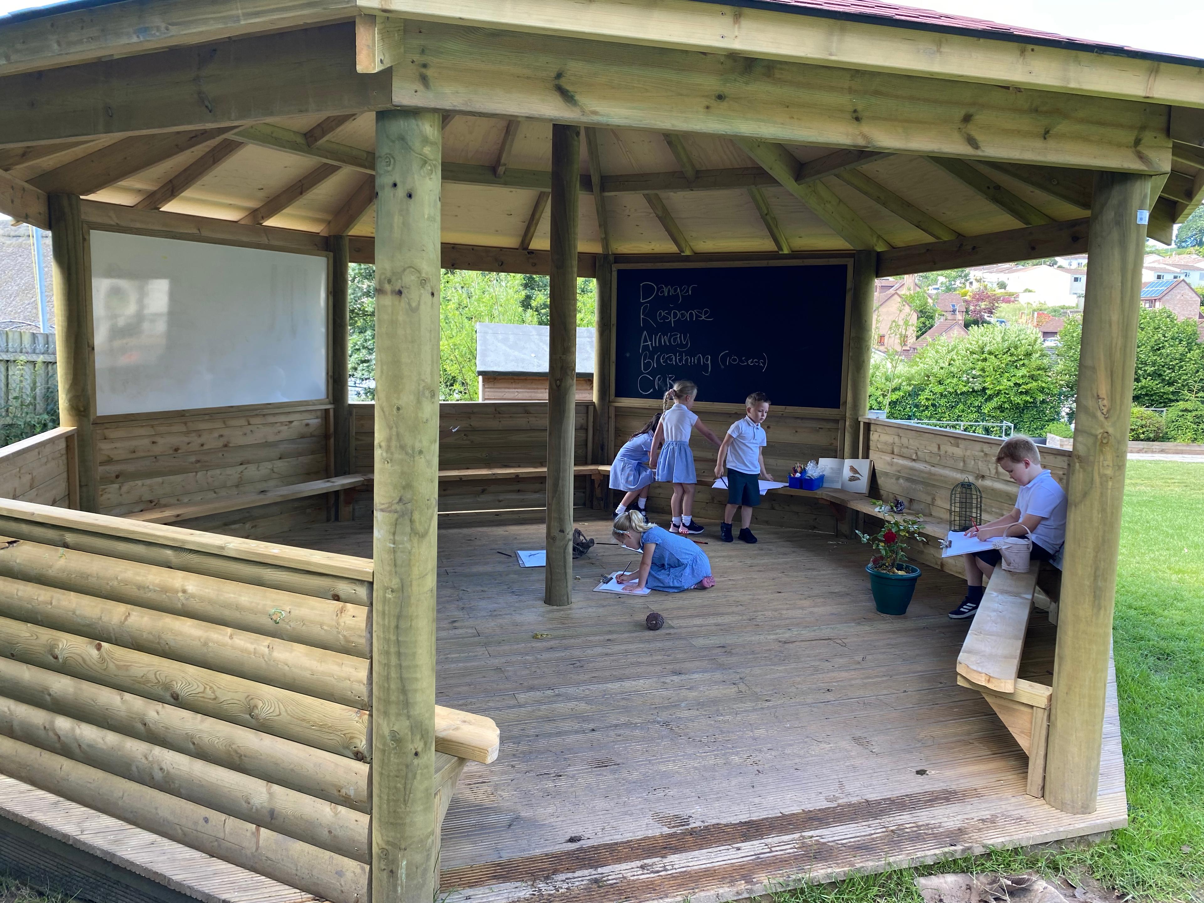 Wooden 6m Octagonal Gazebo with decked base in a school playground.