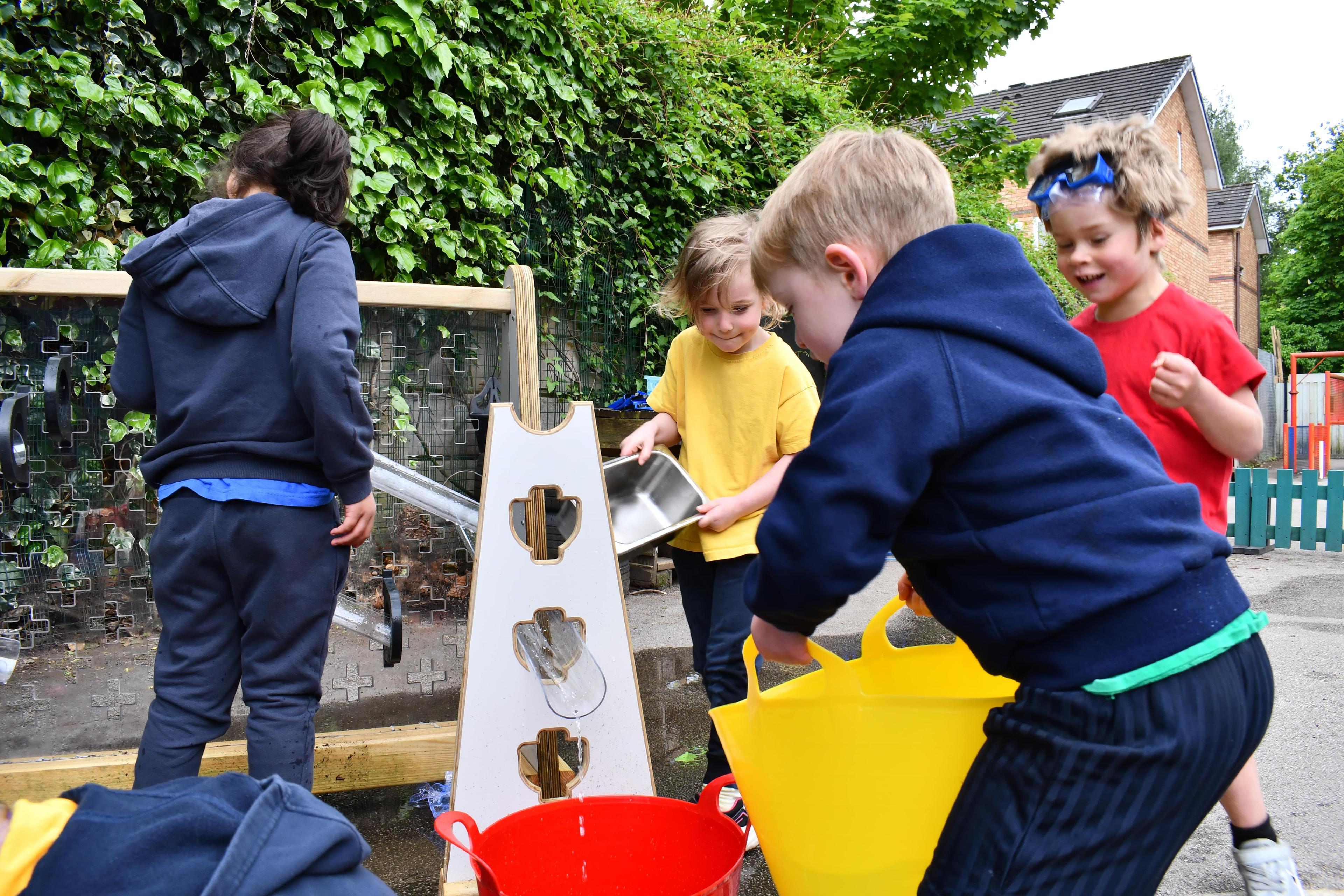A group of early years children are pouring water into the Buttermere Water Play Package.