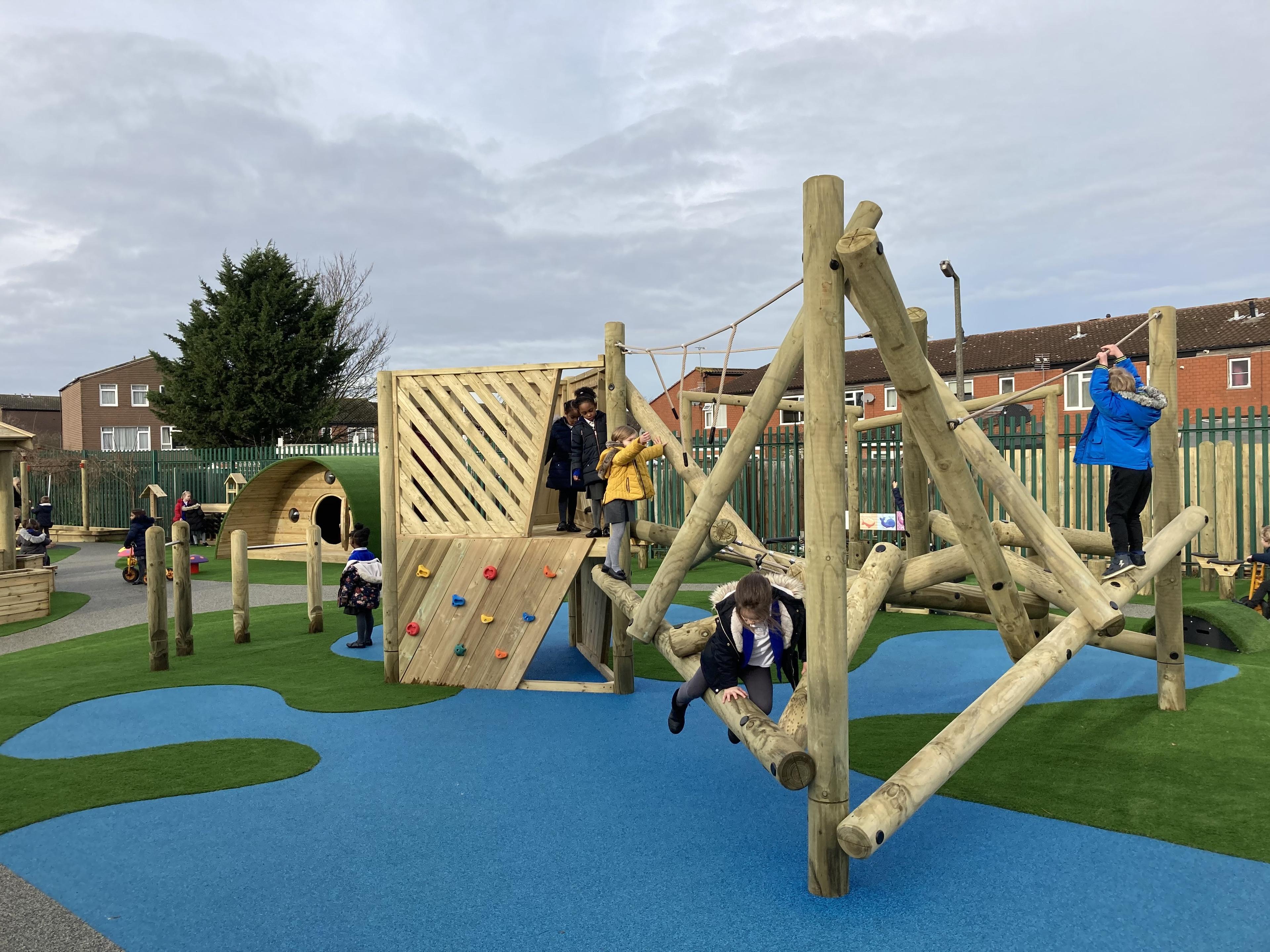 EYFS children are climbing all over the climbing frame, with a few being positioned on the attached platform.
