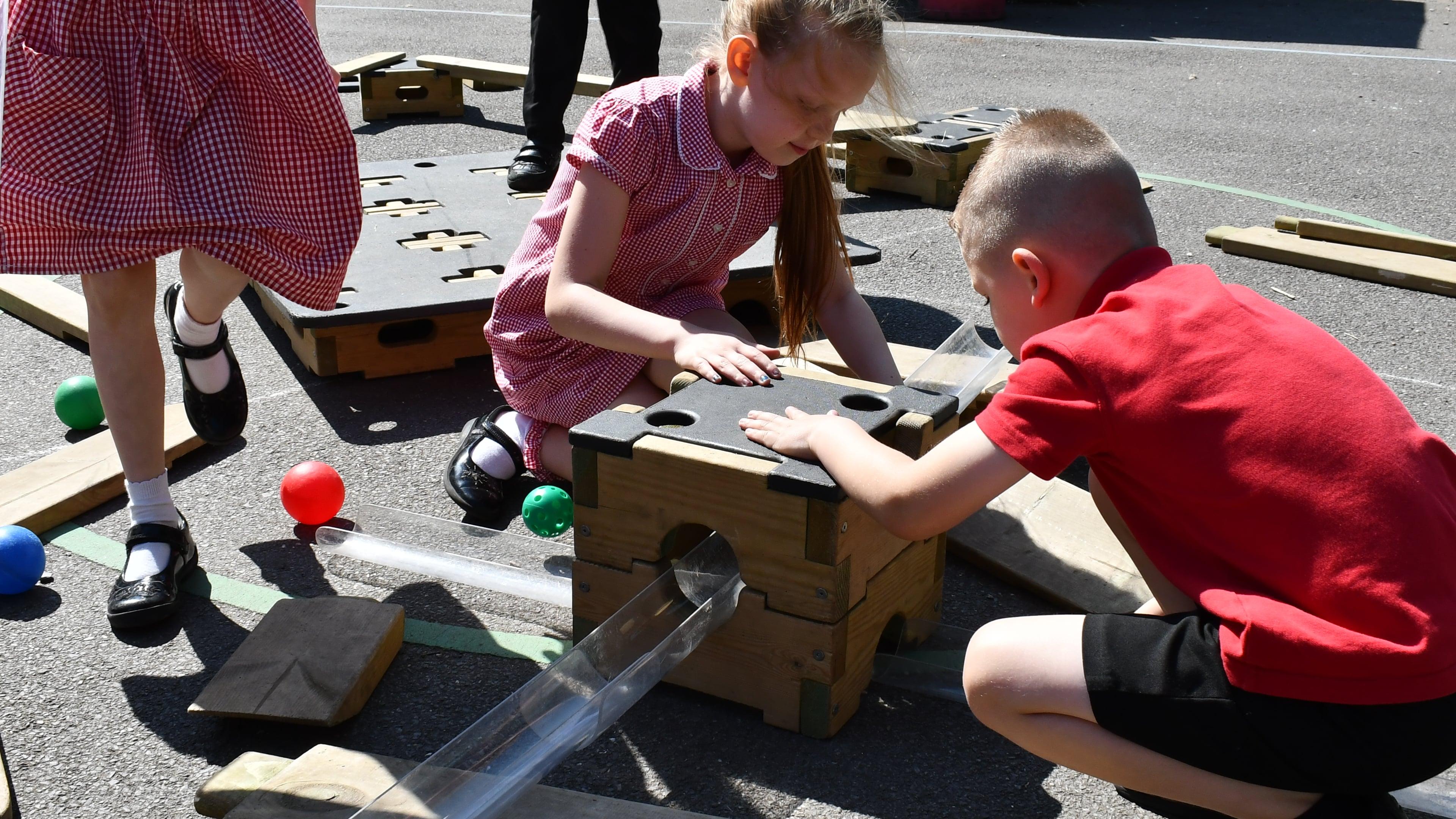 A boy and a girl are putting together the Water Play Builder Package, attaching the plastic lid to the box.