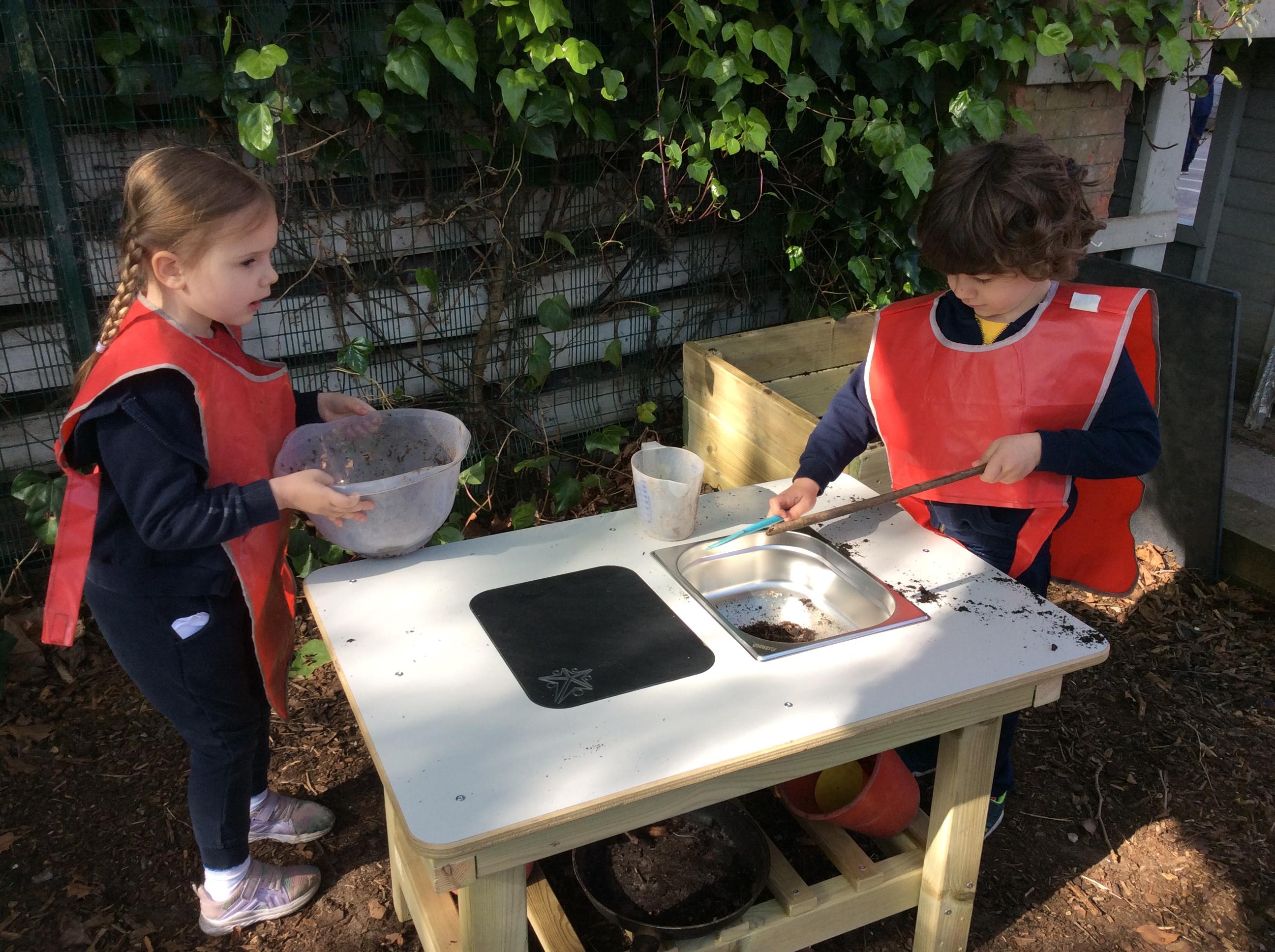 A child playing with the mud kitchen island that makes up part of the Pioneer Messy Play Package