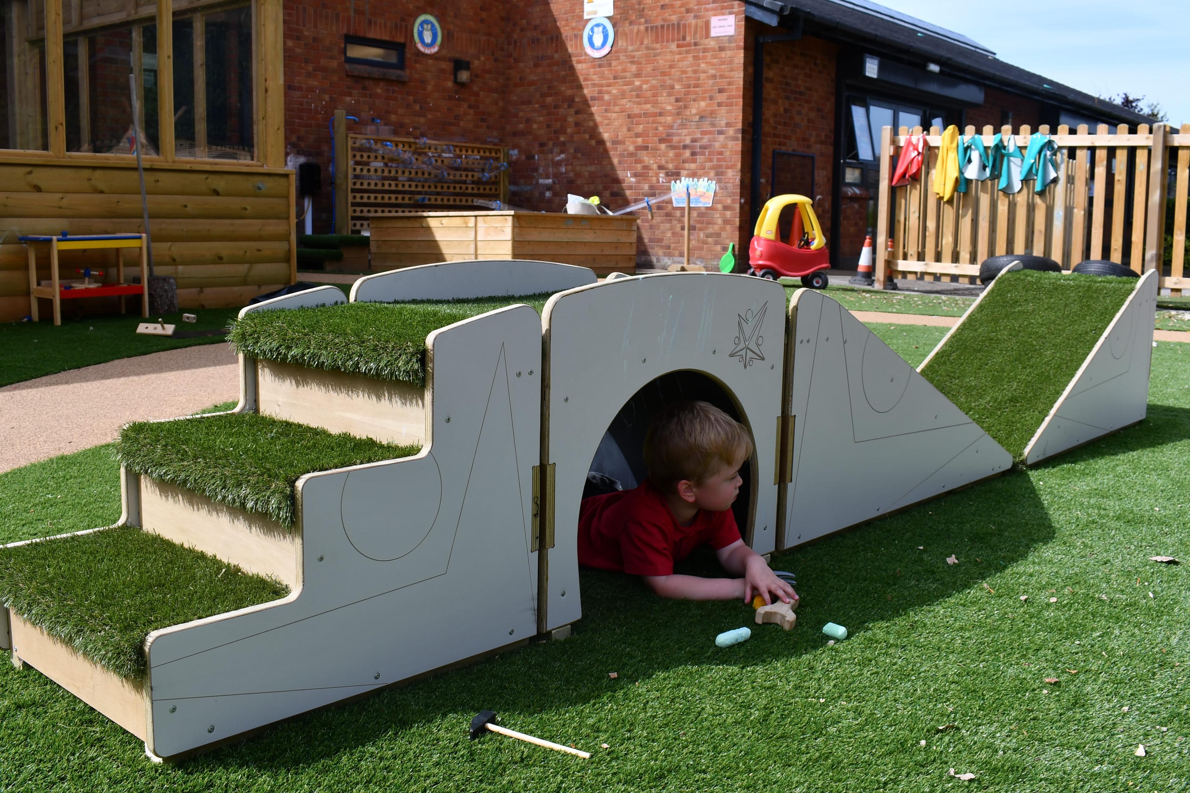A child is crawling through the tunnel of the Up and Under set.